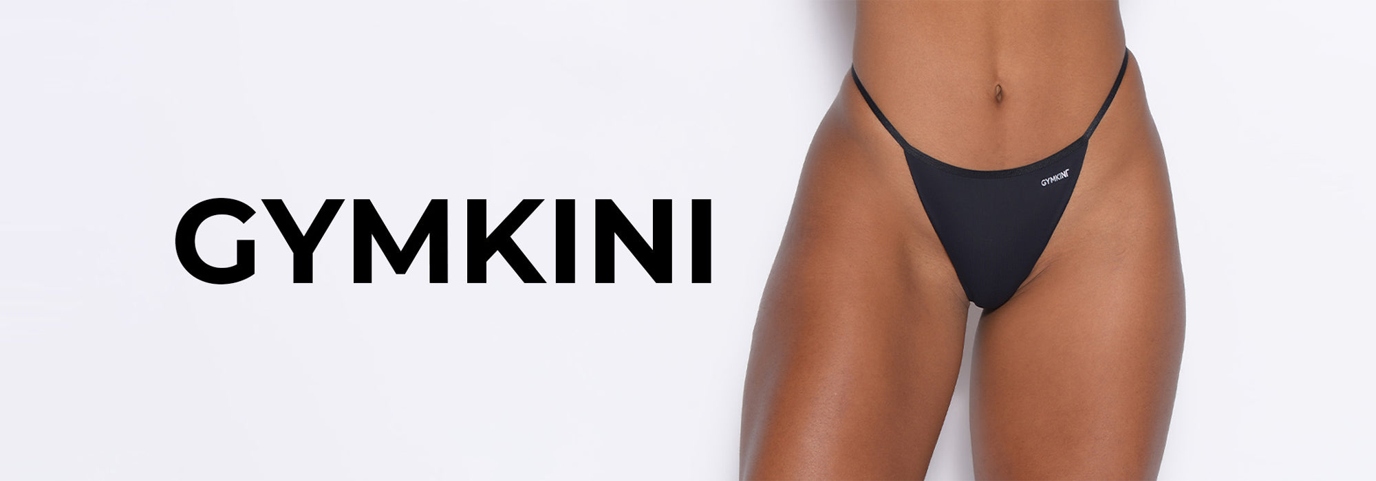 A close-up of a models lower body wearing a black bikini bottom, with the word GYMKINI displayed prominently next to the image