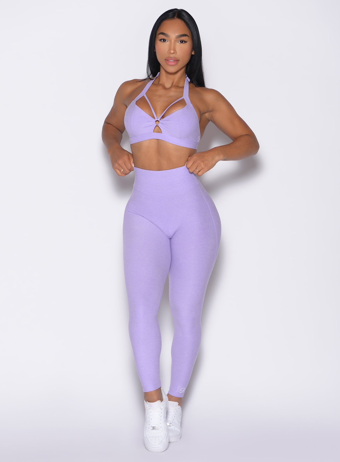 front profile view of a model with both hands on the waistband wearing the Movement Leggings in Sugared Lilac color