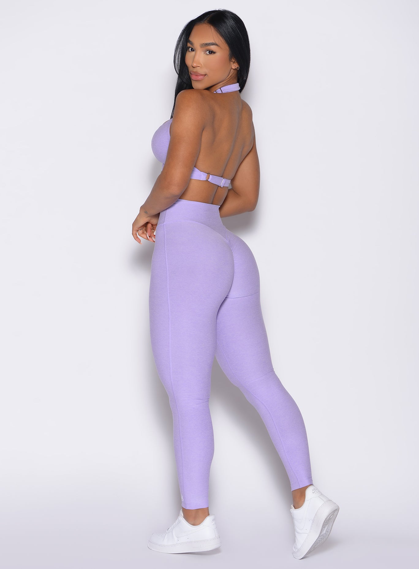 back left side profile view of a model looking over her shoulder wearing the Movement Leggings in Sugared Lilac color