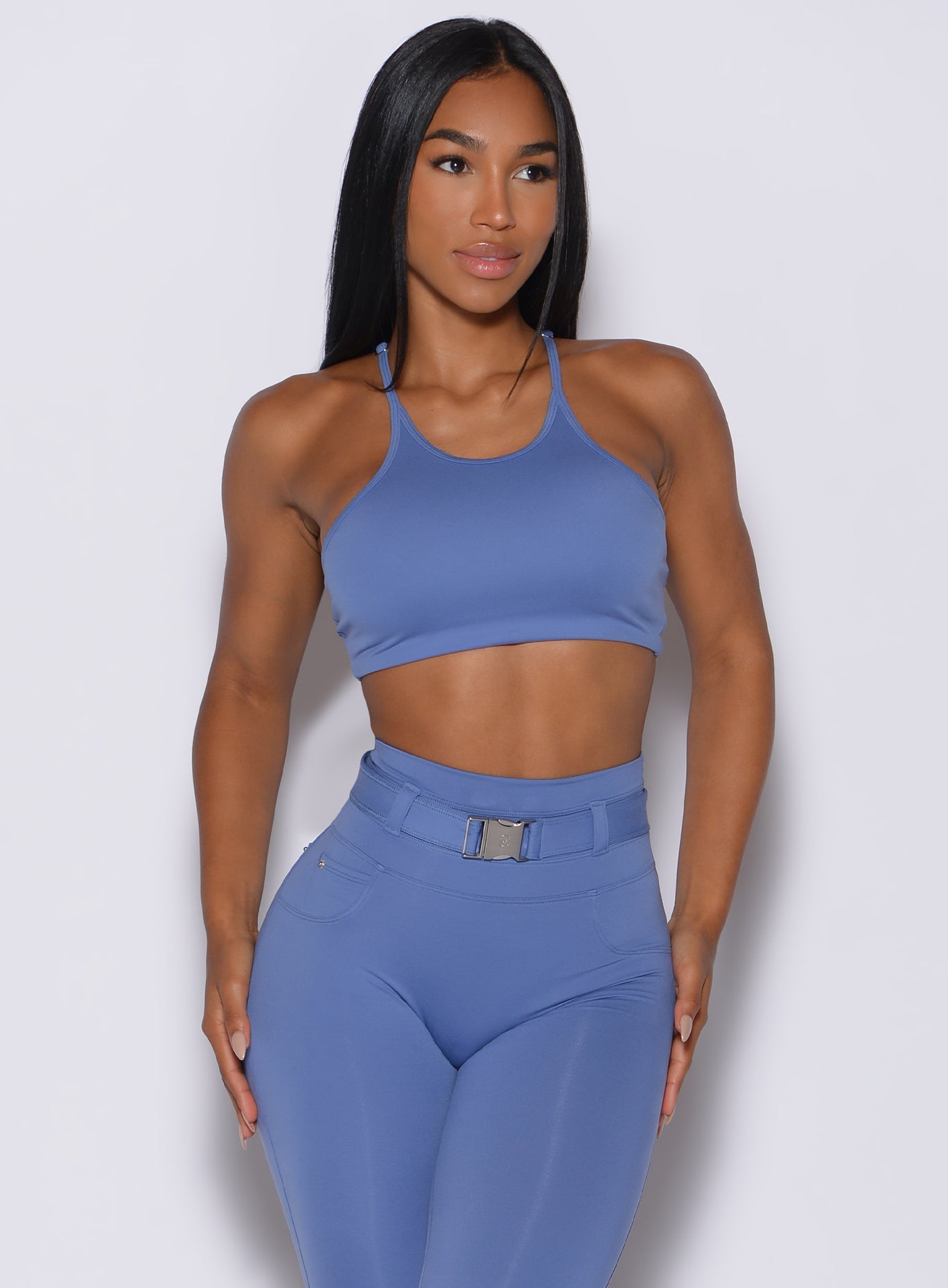 front profile view of a model facing forward wearing our high neck crop bra in denim blue color along with the matching leggings