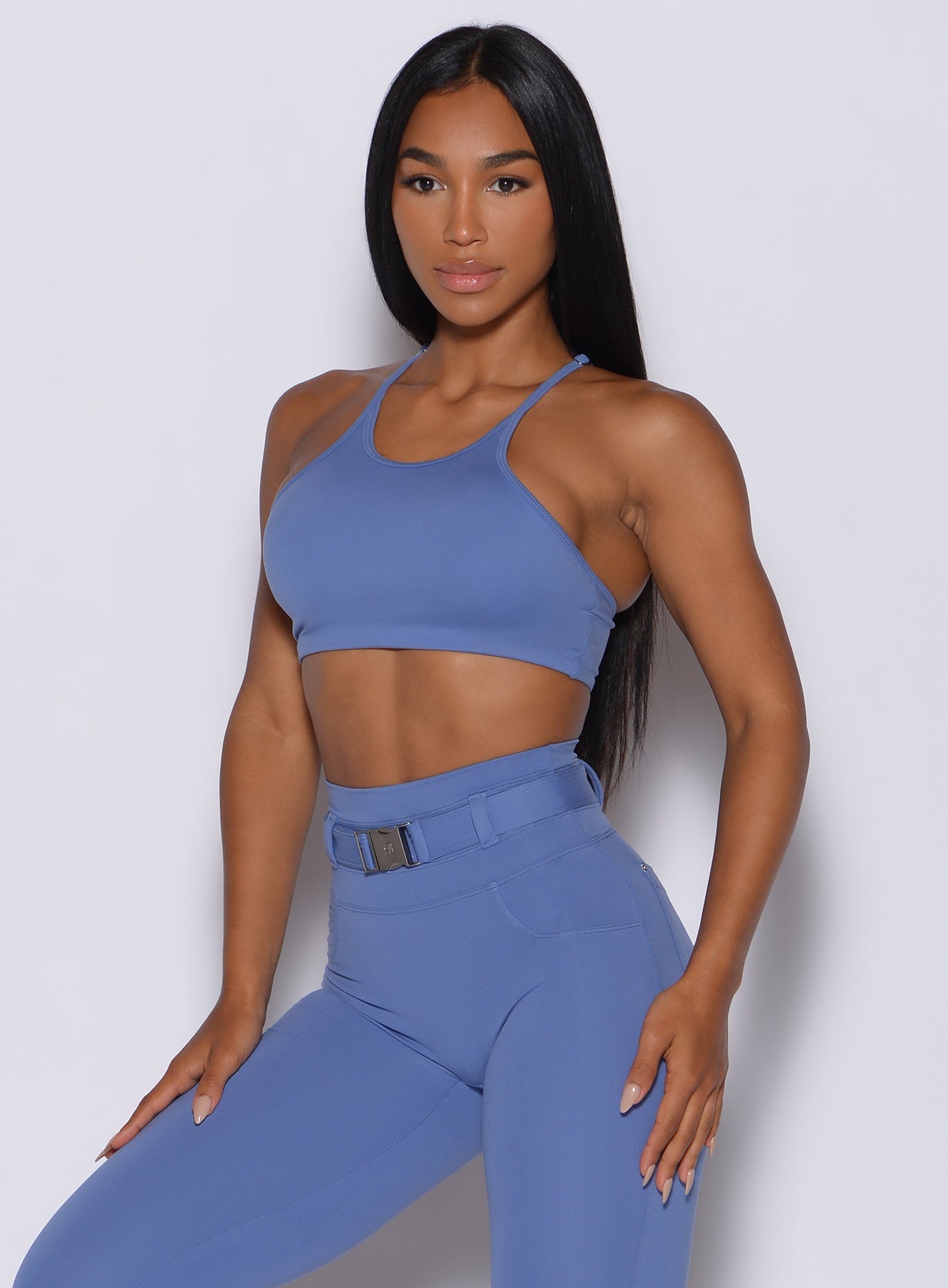 front profile view of a model angled slightly to her left wearing our high neck crop bra in denim blue color along with the matching leggings
