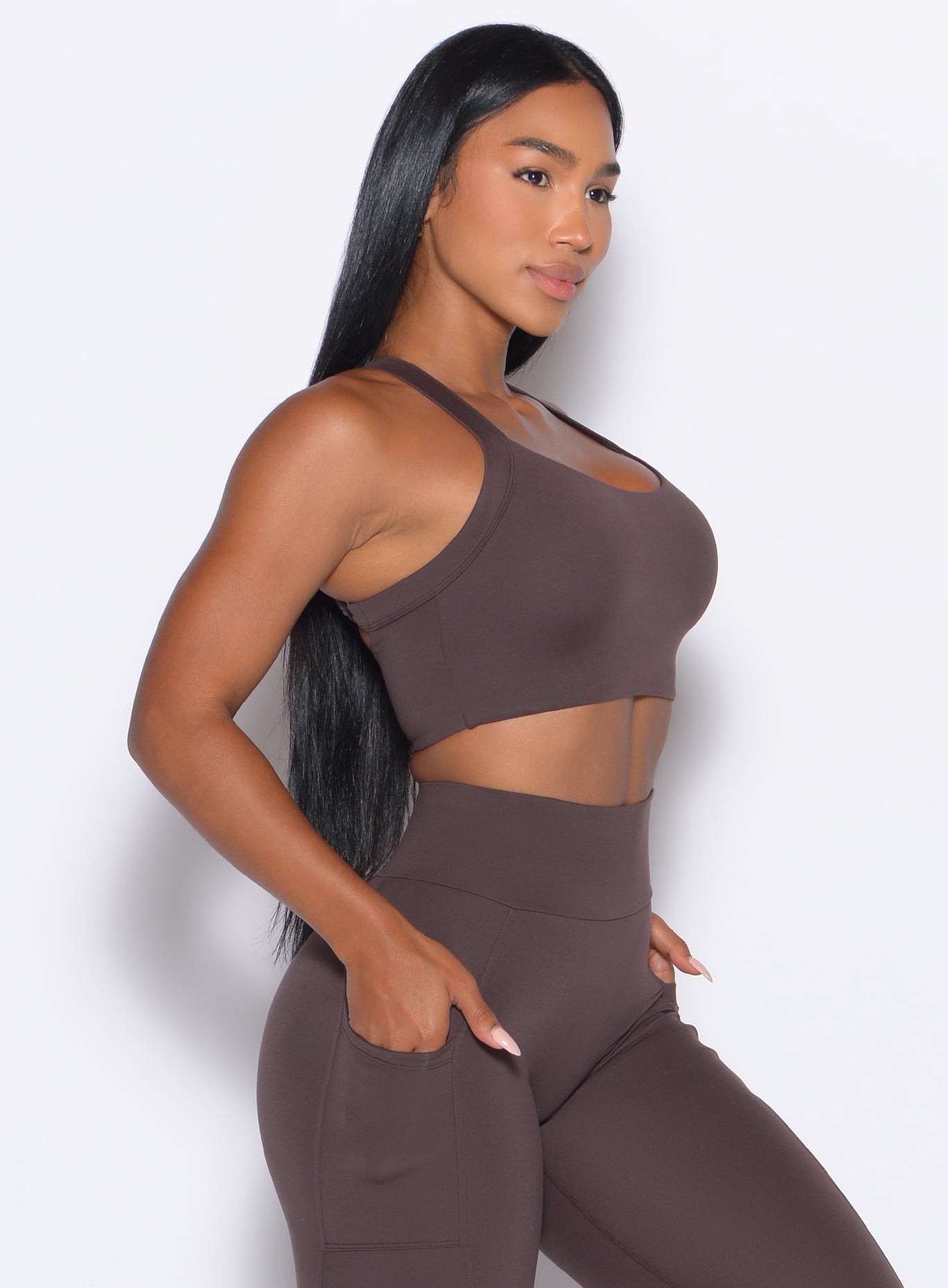right side profile view of a model facing forward wearing our High Impact Bra in Seal Brown color and the matching leggings