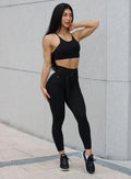 front side profile view of a model wearing our black peach bottoms leggings along with the matching sports bra