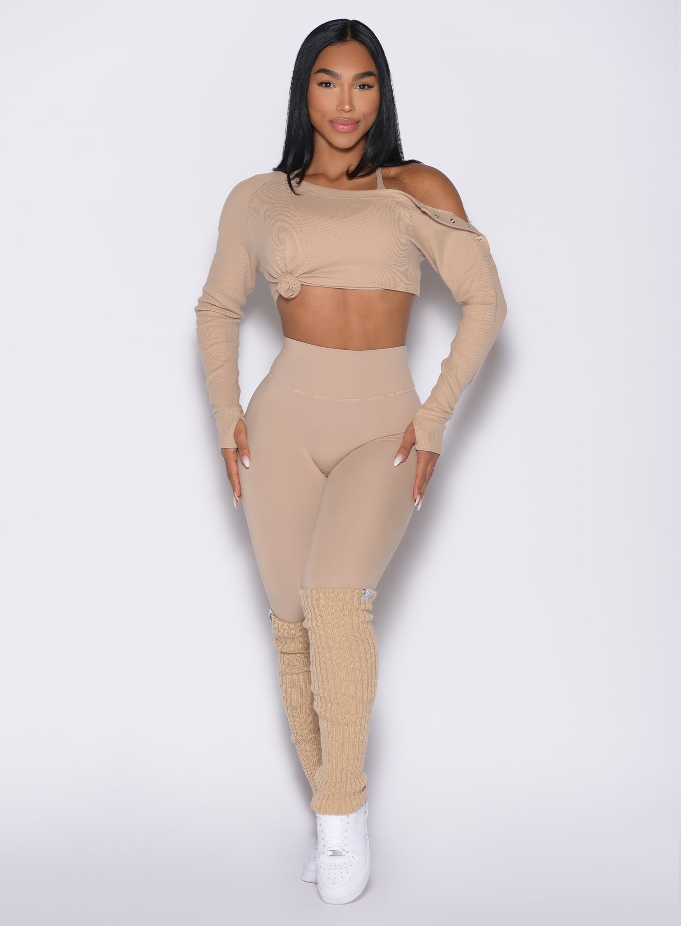 front profile view of a model wearing the Luxe Leg Warmers in glacial beige color paired with the matching pullover