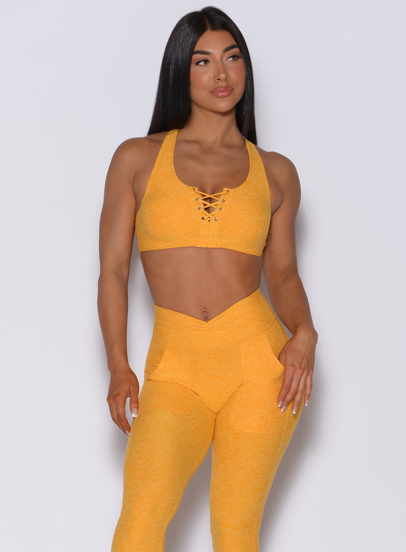 Front profile view of a model wearing our laced crop bra in sunkissed color and a matching leggings