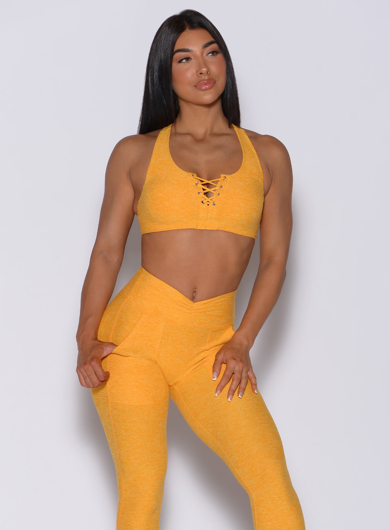Front profile view of a model in our laced crop bra in sunkissed color and a matching leggings