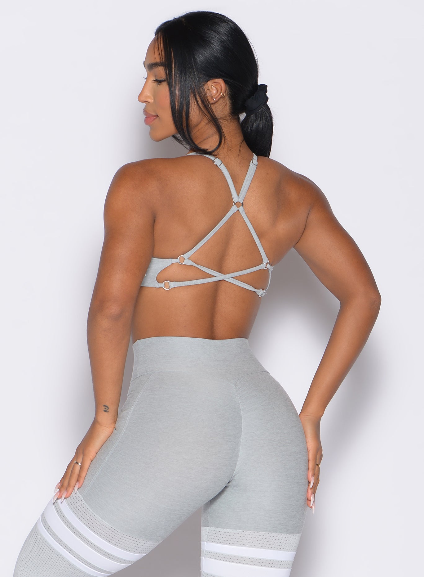 back profile view of a model facing to the left side wearing the Lift Luxe Sports bra in light cloud color