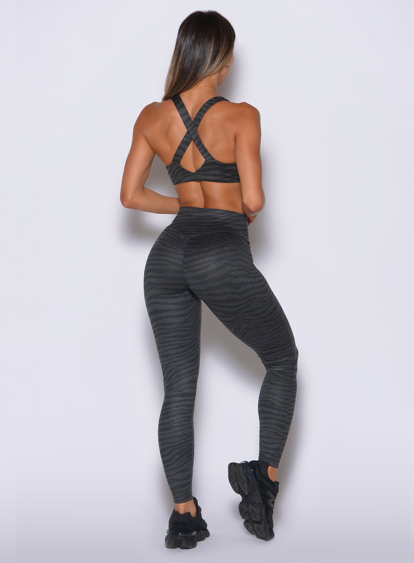 The rear view showcases hidden scrunch lift and a sweetheart glute seam in charcoal zebra print