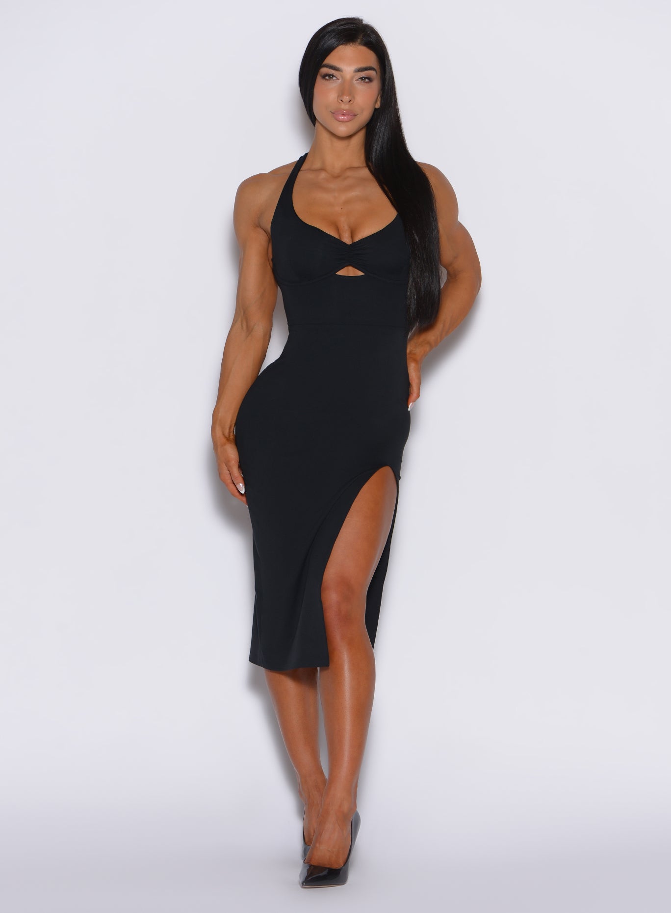 front profile view of a model facing forward wearing our black dress with a high side slit on the left