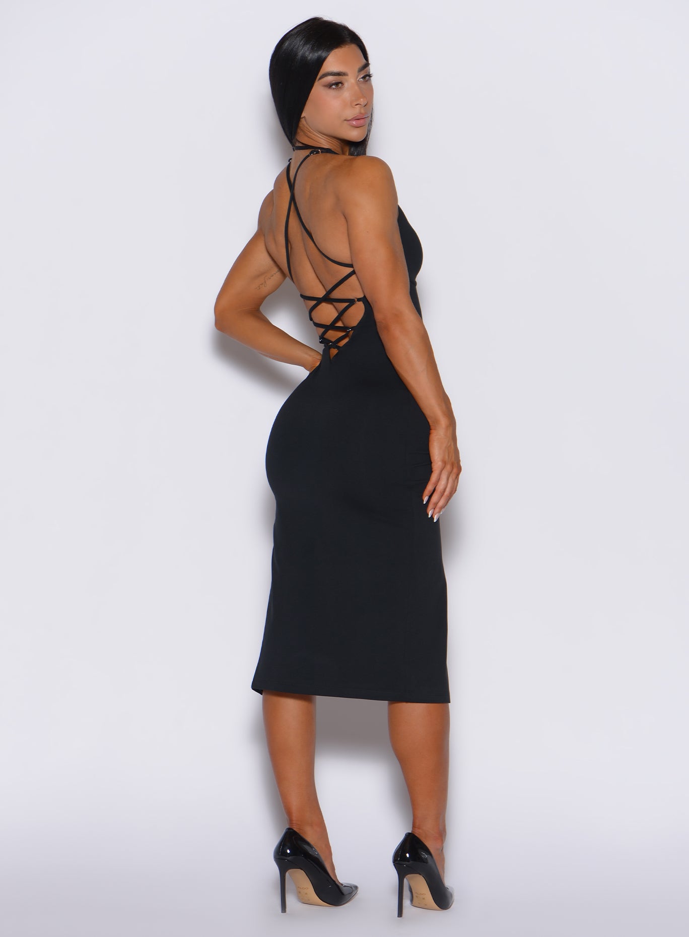 back profile view of a model wearing our black dress with a criss cross design at the back