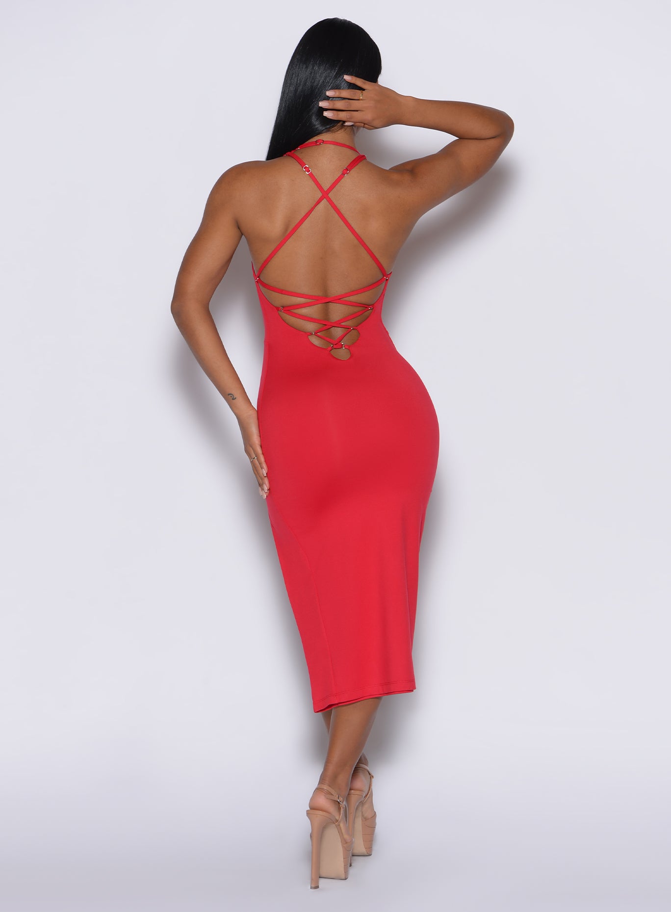 back  profile view of a model wearing our bright red dress with criss cross adjustable straps at the back