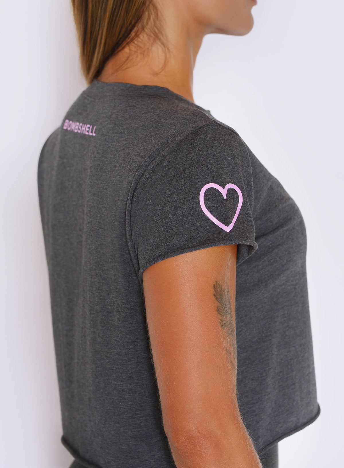 Close-up side profile displaying heart sleeve accent and raw-edge finish on heathered charcoal fabric.