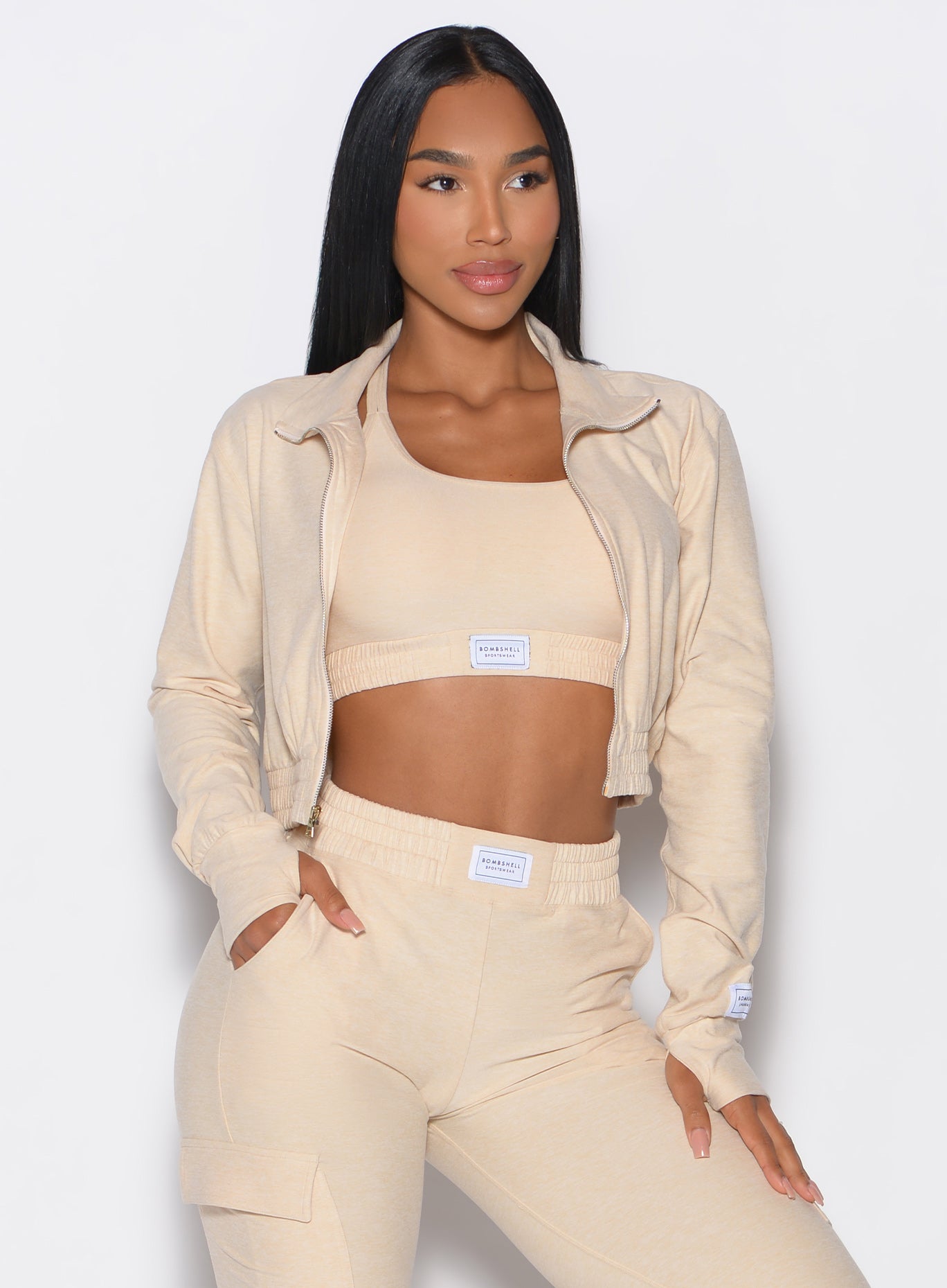 front profile view of our model wearing the Cloud Crop Jacket in vanilla color with one hand in the pocket of the matching joggers looking to the left