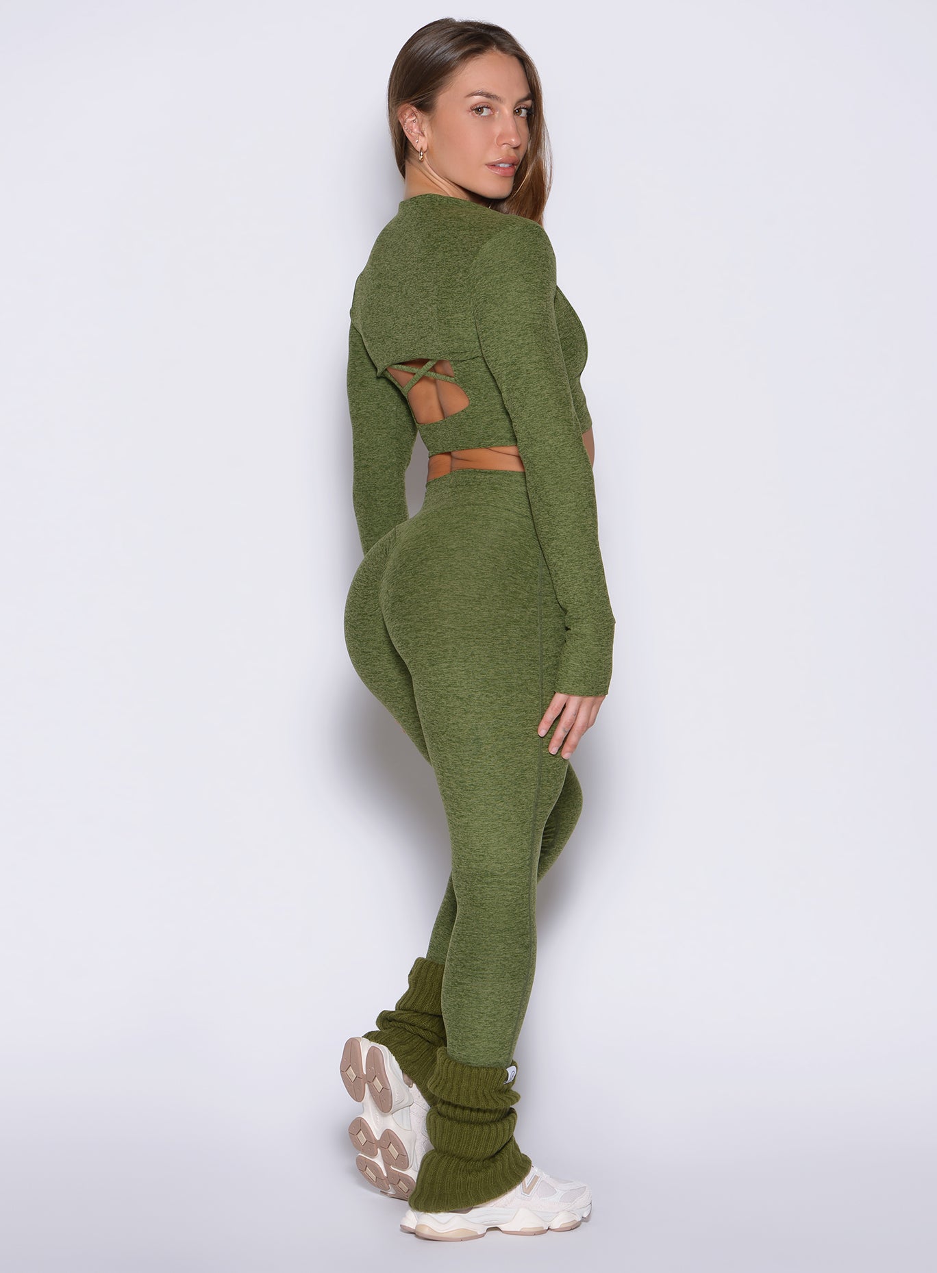 right side view of a model looking over her shoulders wearing the Luxe Leg warmers-short in Juniper color