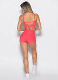back profile view of a model facing to the left side wearing the Movement Short Shorts in watermelon punch color