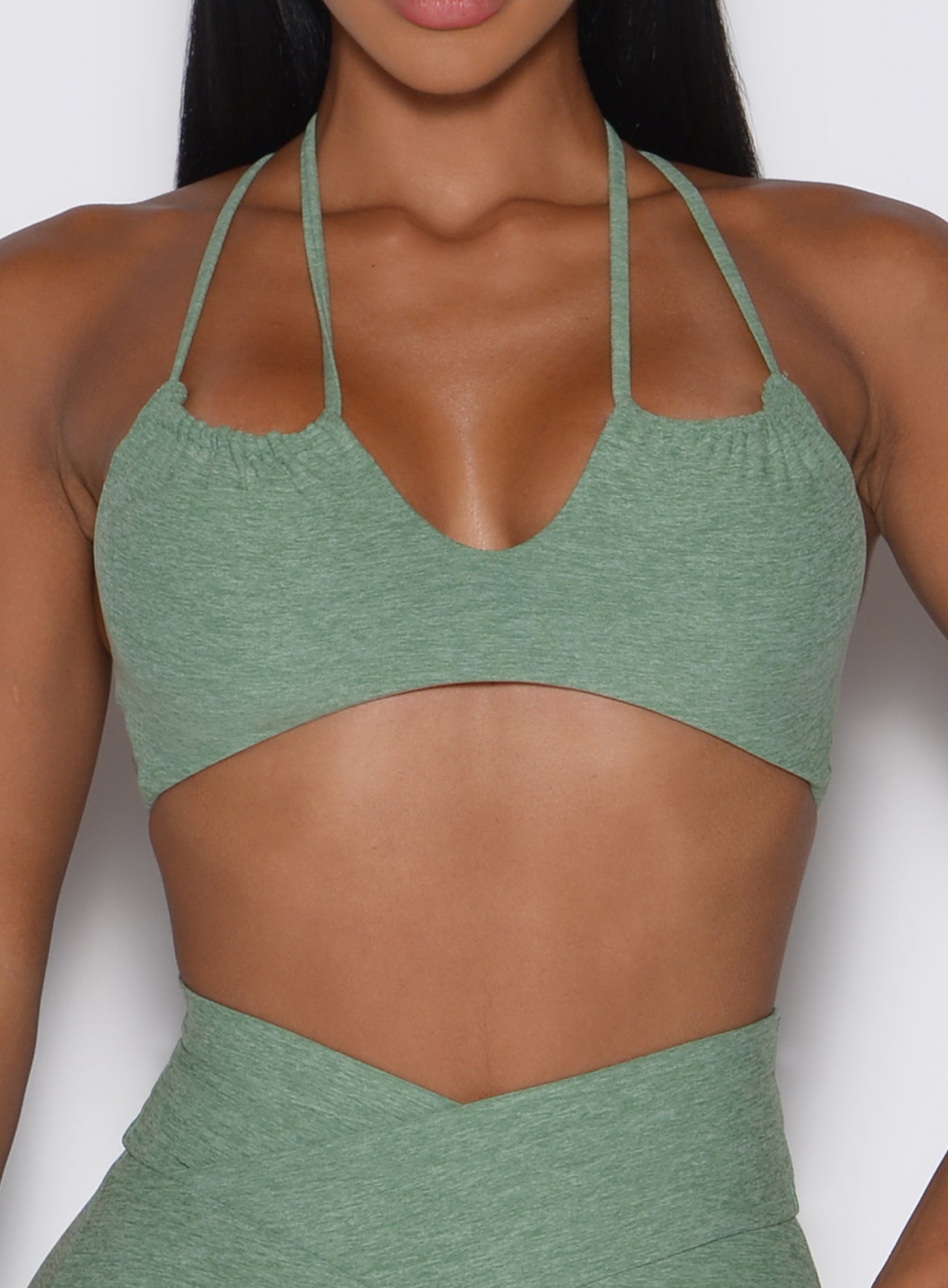 close up front view of a model wearing the MulTie Sports Bra in basil color