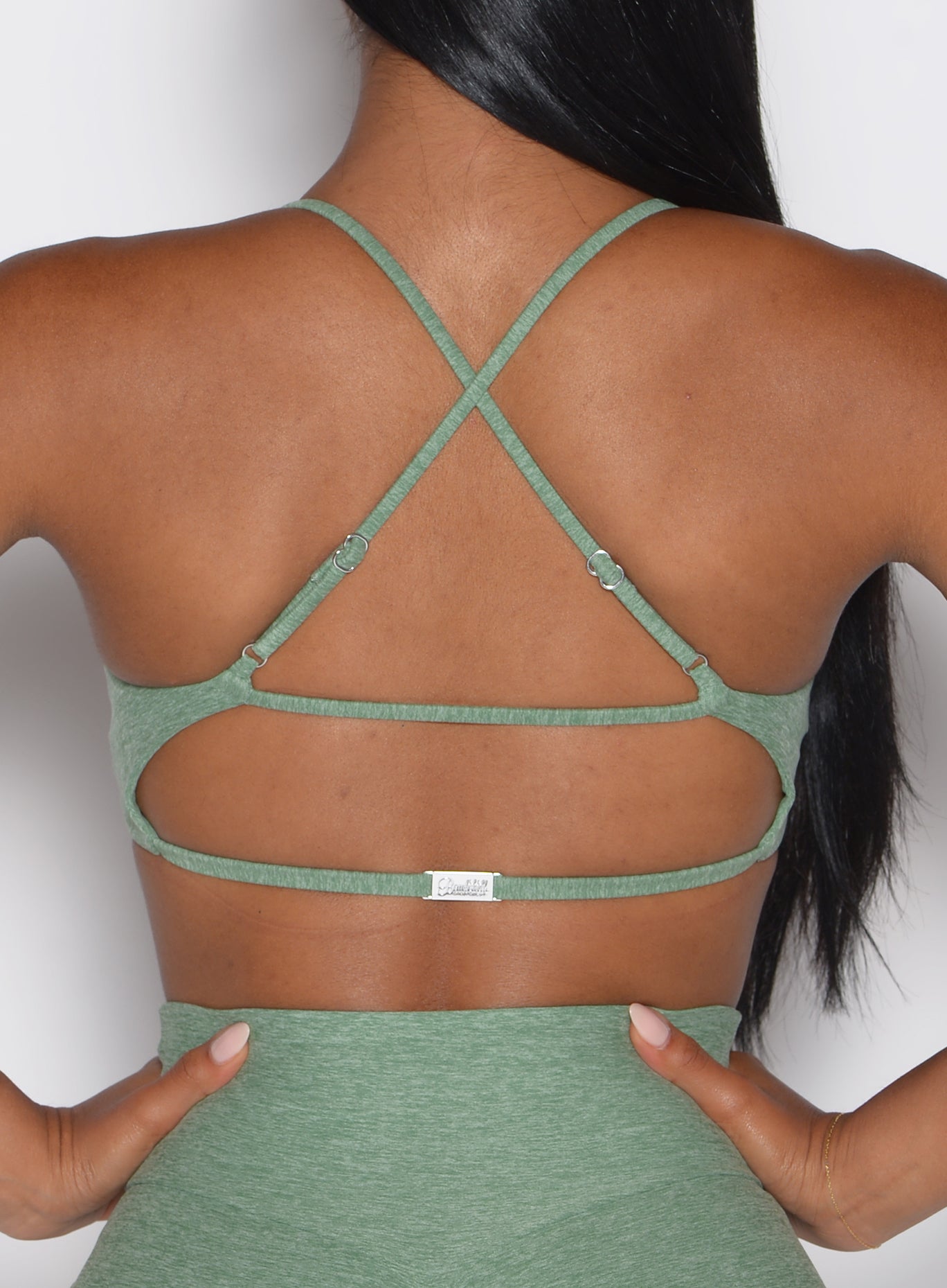 close up back profile view of a model wearing the MulTie Sports Bra in basil color