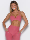 Woman wearing a pink sports bra and leggings set on a white background