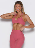 Side front view os woman wearing a pink sports bra and leggings set on a white background