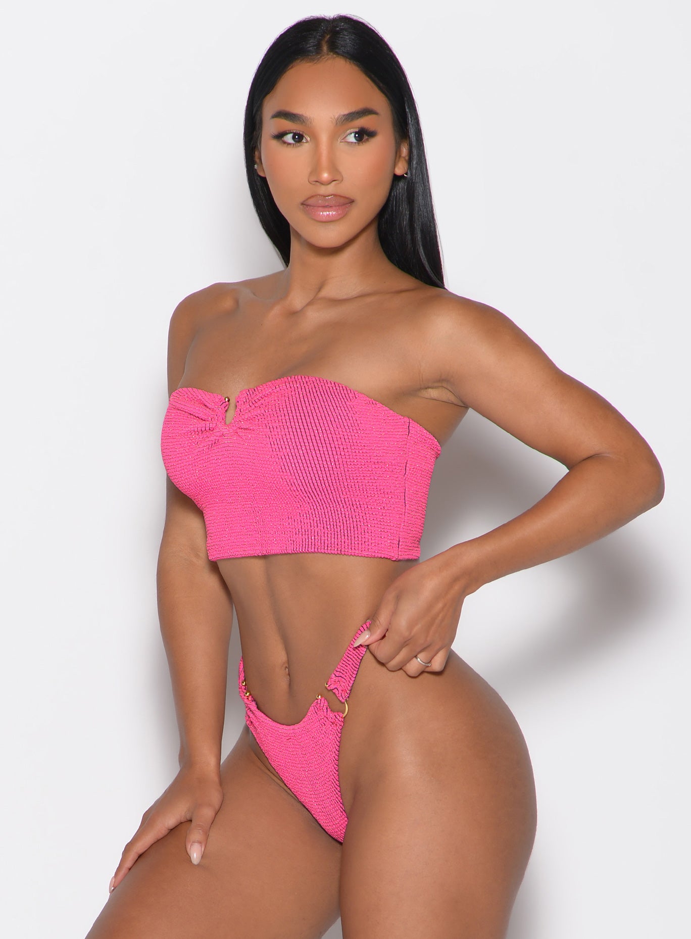 front left side profile view of a model looking to the left side wearing the Neon Nights Bikini Bandeau in Pink Passion color