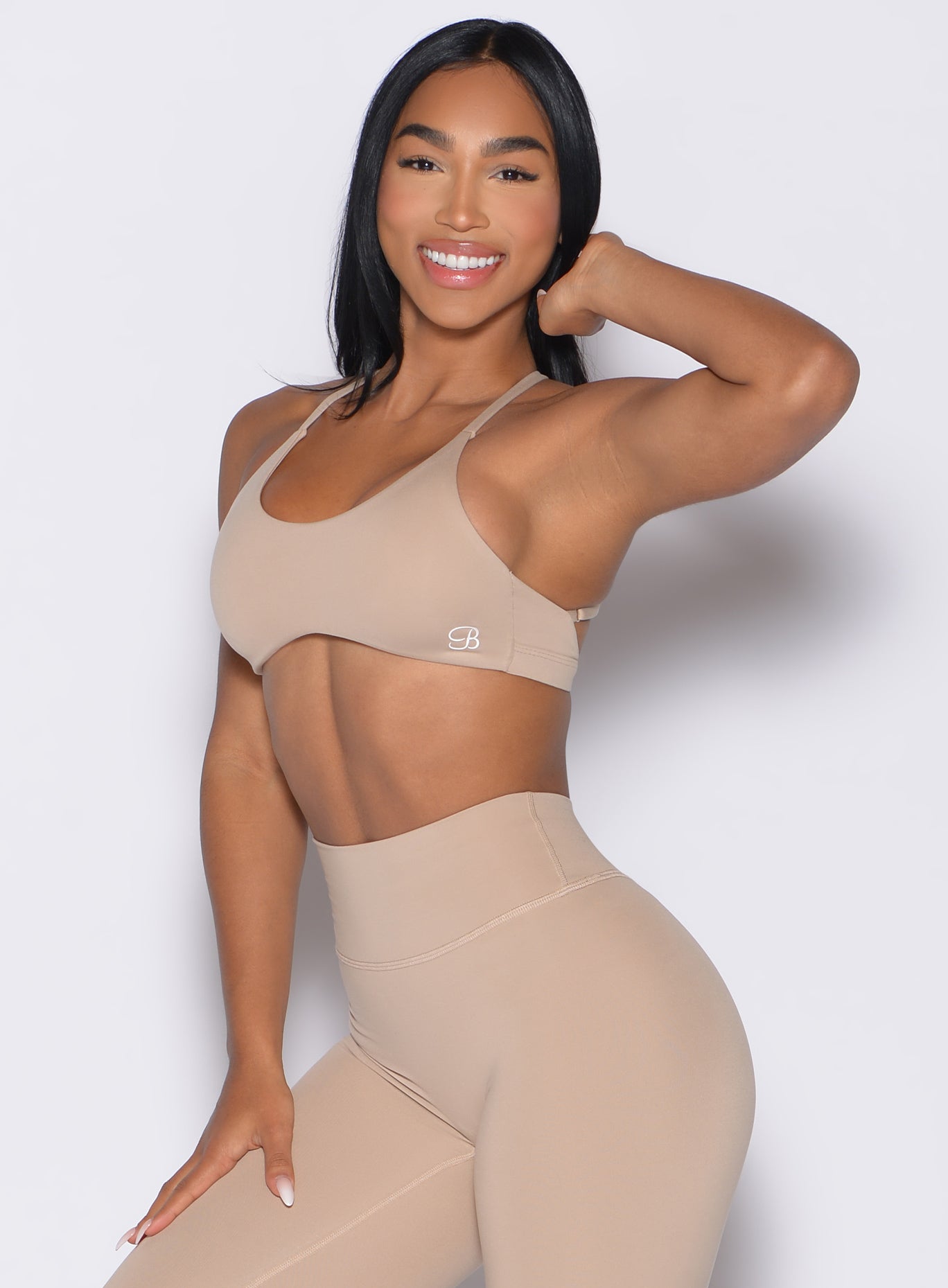 front left side profile view of a model wearing the Passion Sports Bra in glacial beige color paired with the matching leggings
