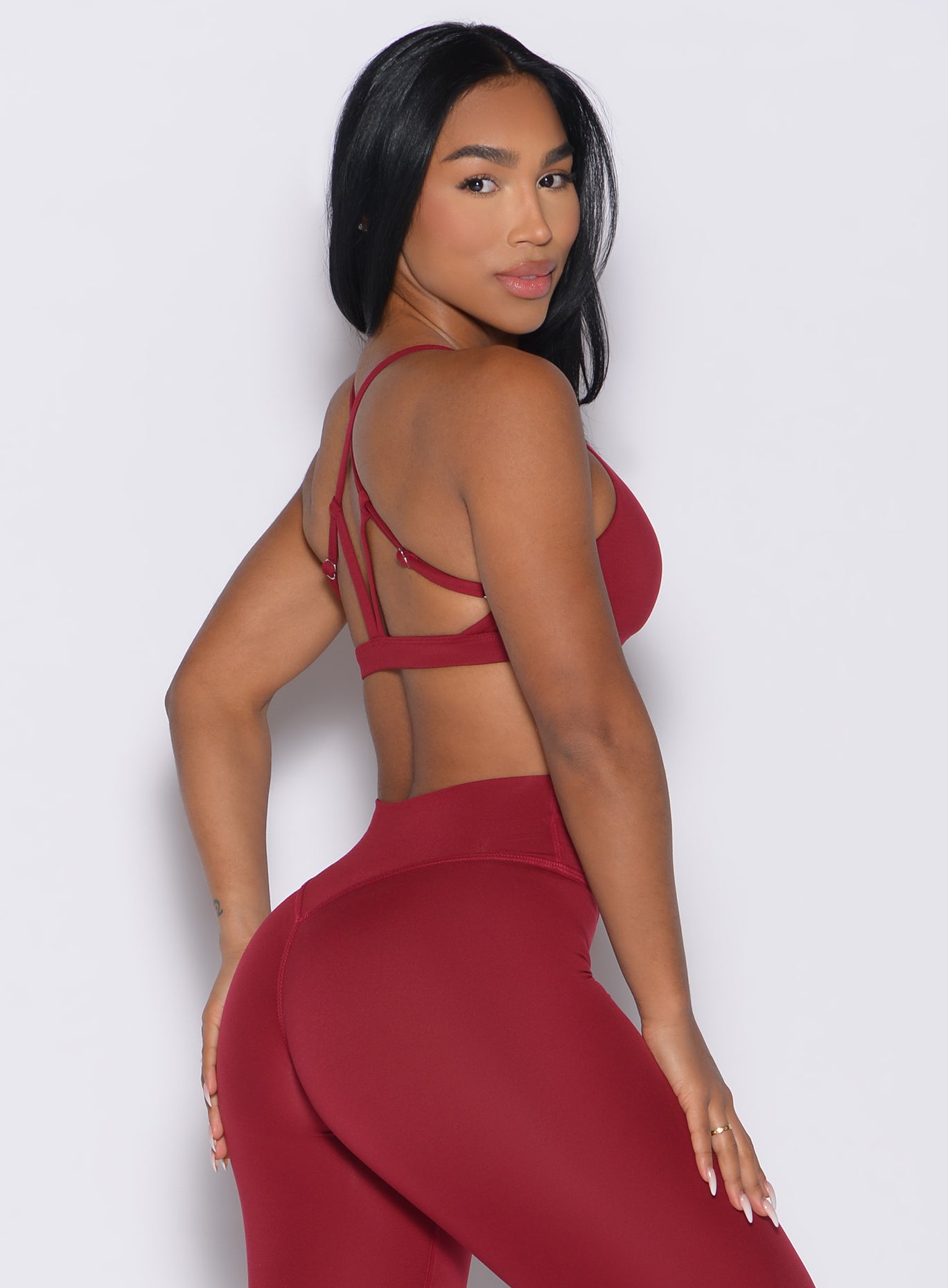 right side profile view of a model looking over her shoulder wearing the Passion Sports Bra in red velvet color