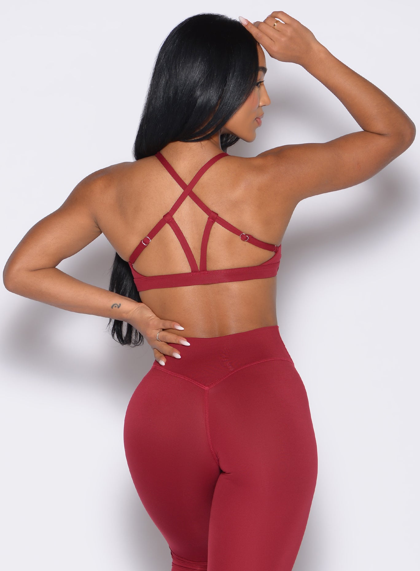 back profile view of a model wearing the Passion Sports Bra in red velvet color paired with the matching leggings