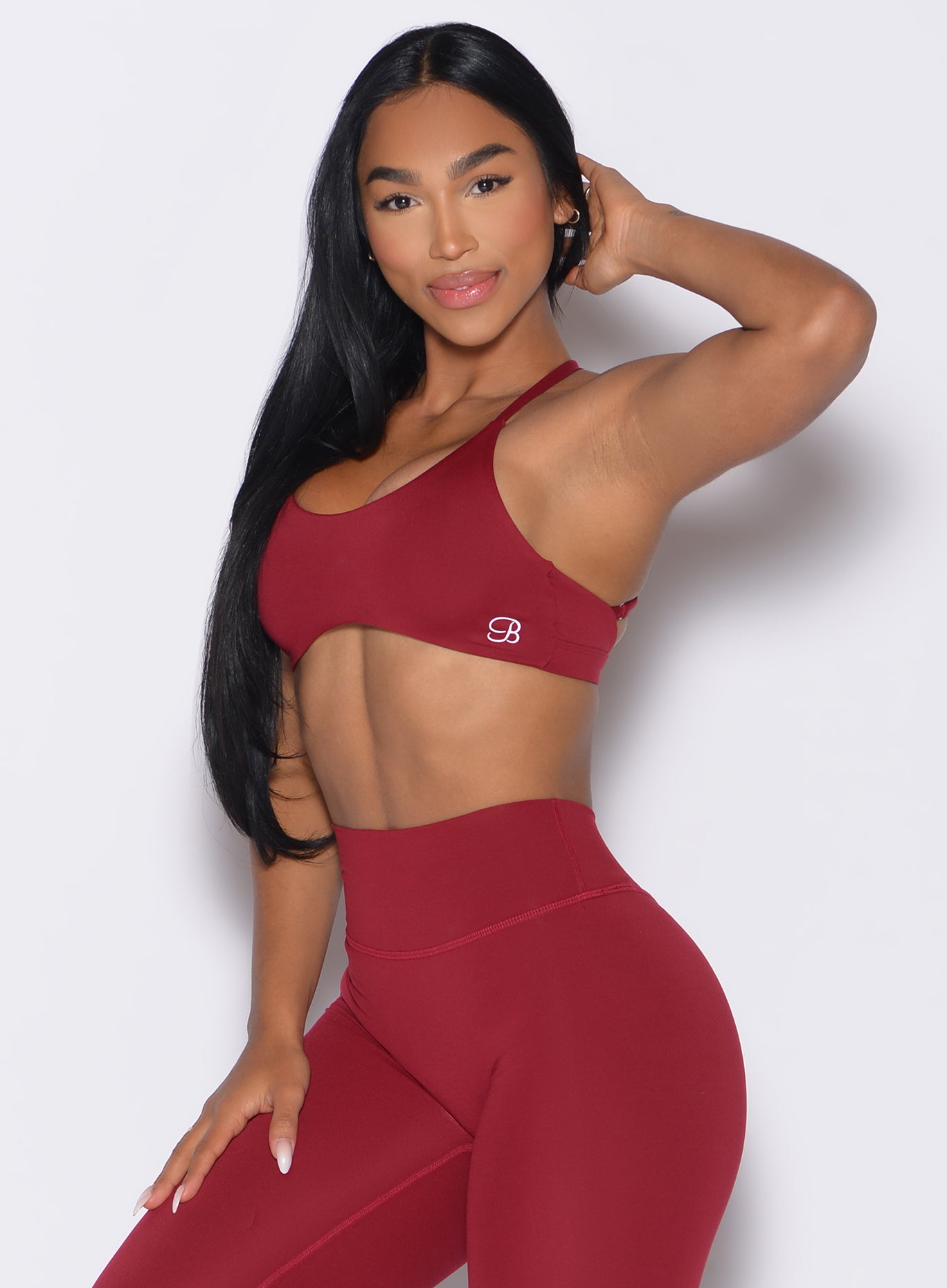 front left side profile view of a model wearing the Passion Sports Bra in red velvet color paired with the matching leggings
