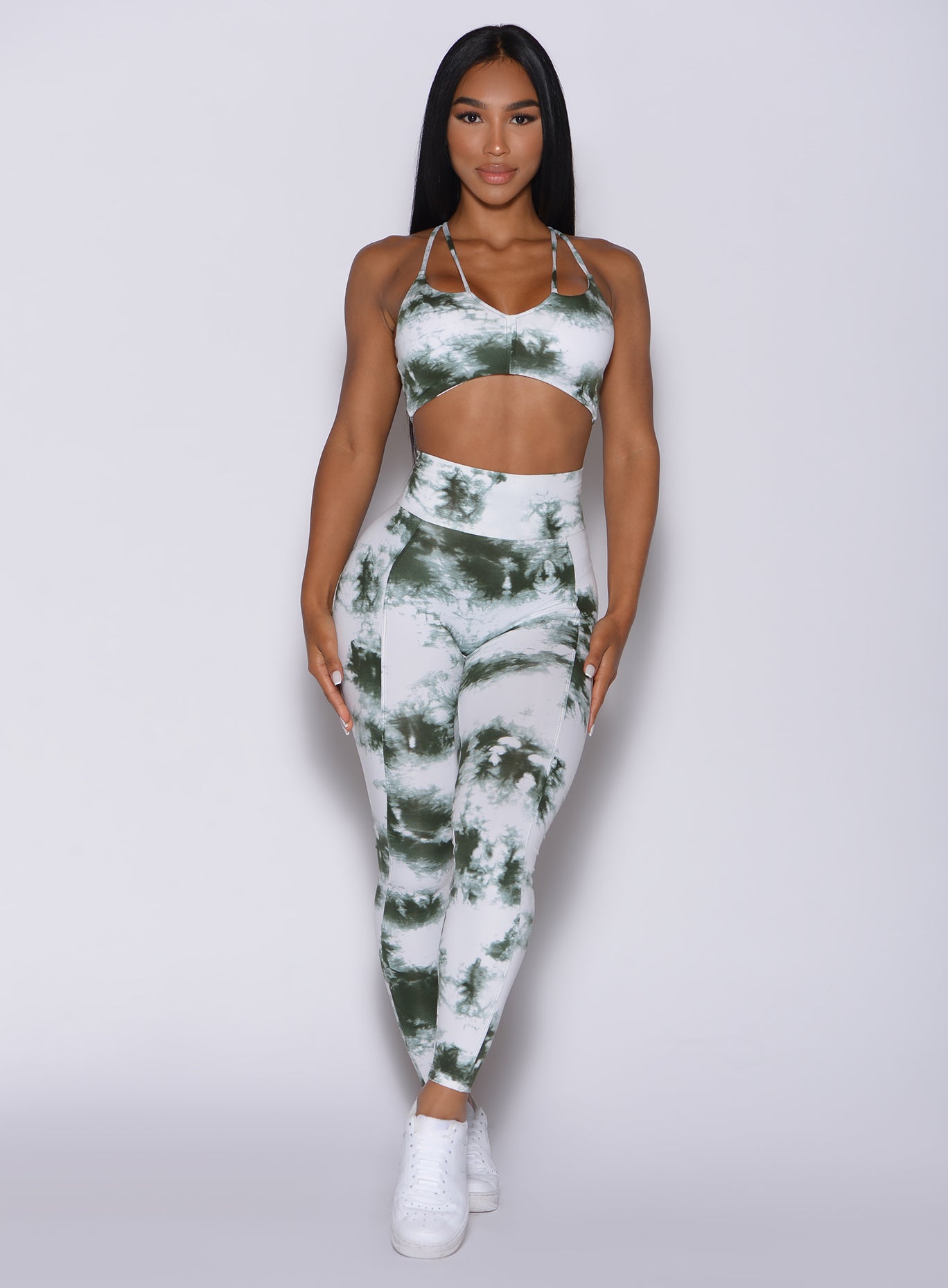 Front profile view of a model wearing our tie dye peach booty leggings in green white and a matching bra