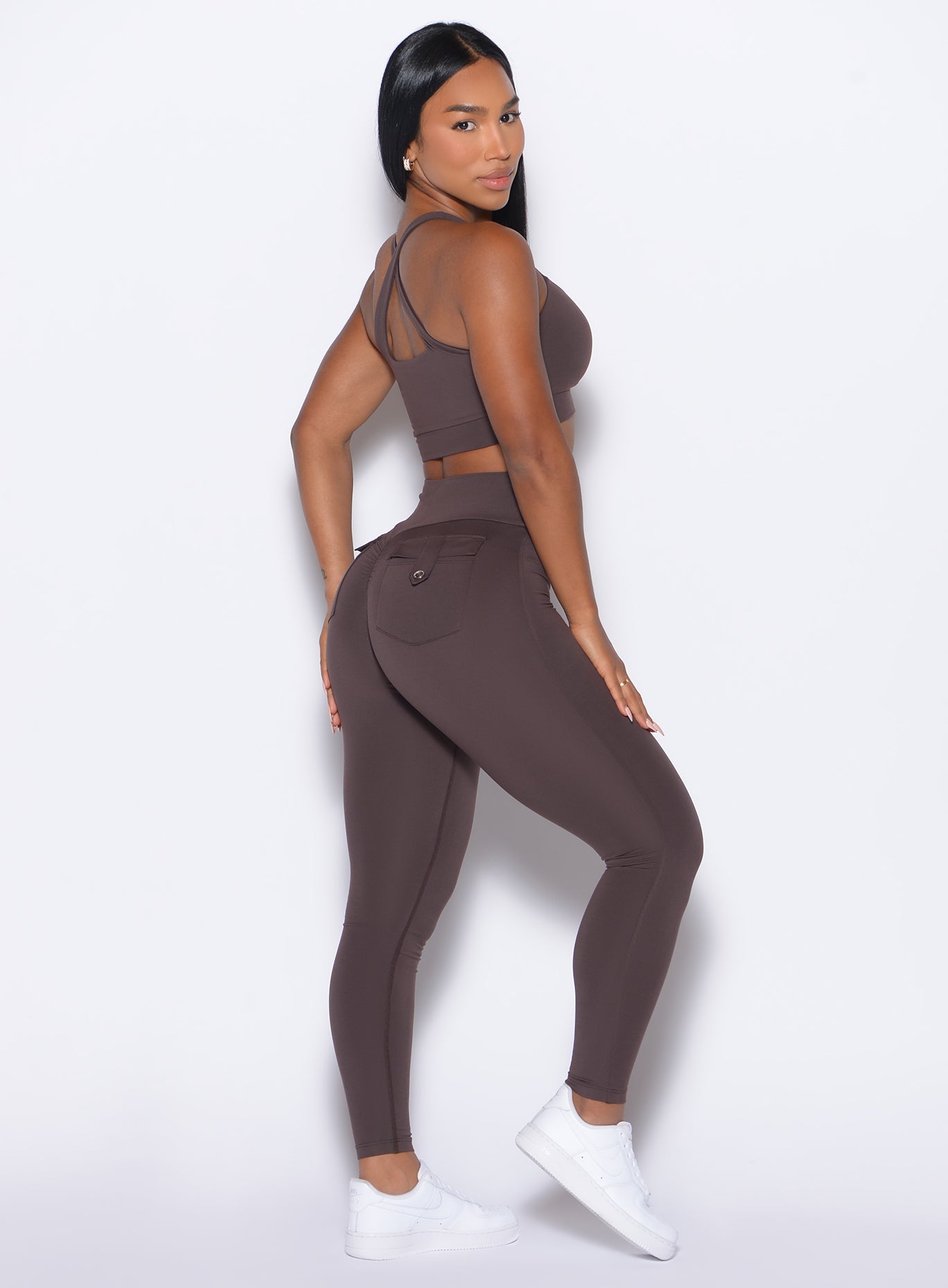 Right side view of a model facing to her right wearing our Pocket Pop Leggings 2.0 in Seal Brown color and the matching bra