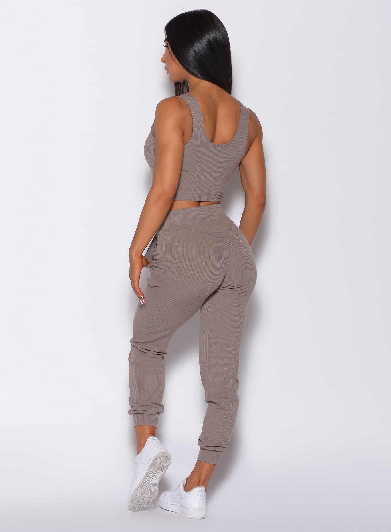 Back profile view of a model angled slightly to her left wearing our comfort rib joggers in navy and a matching bra