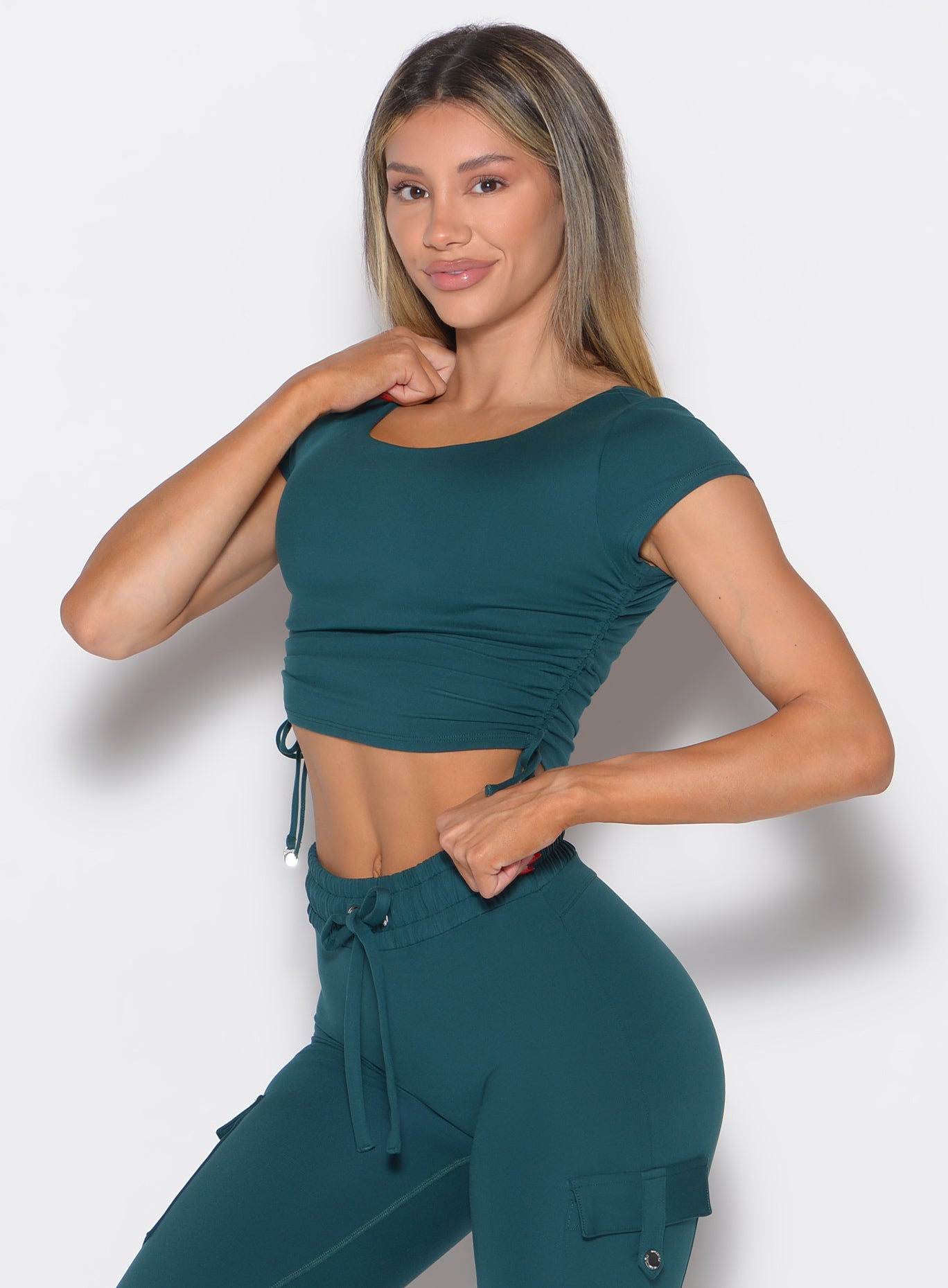 front profile view of a model wearing the Scrunch Fit Bra-Tee in dark sea color paired with the matching leggings