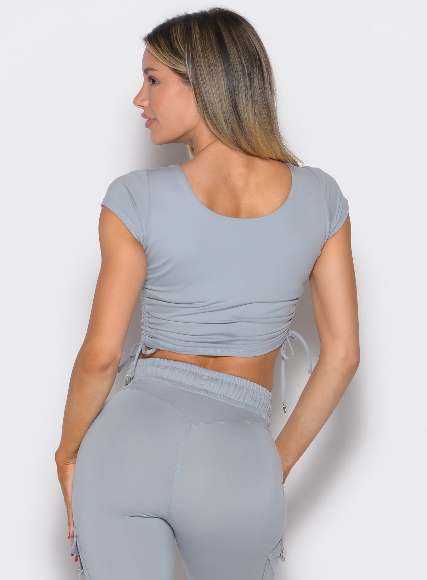back profile view of a model facing to the left wearing the Scrunch Fit Bra-Tee in quarry color