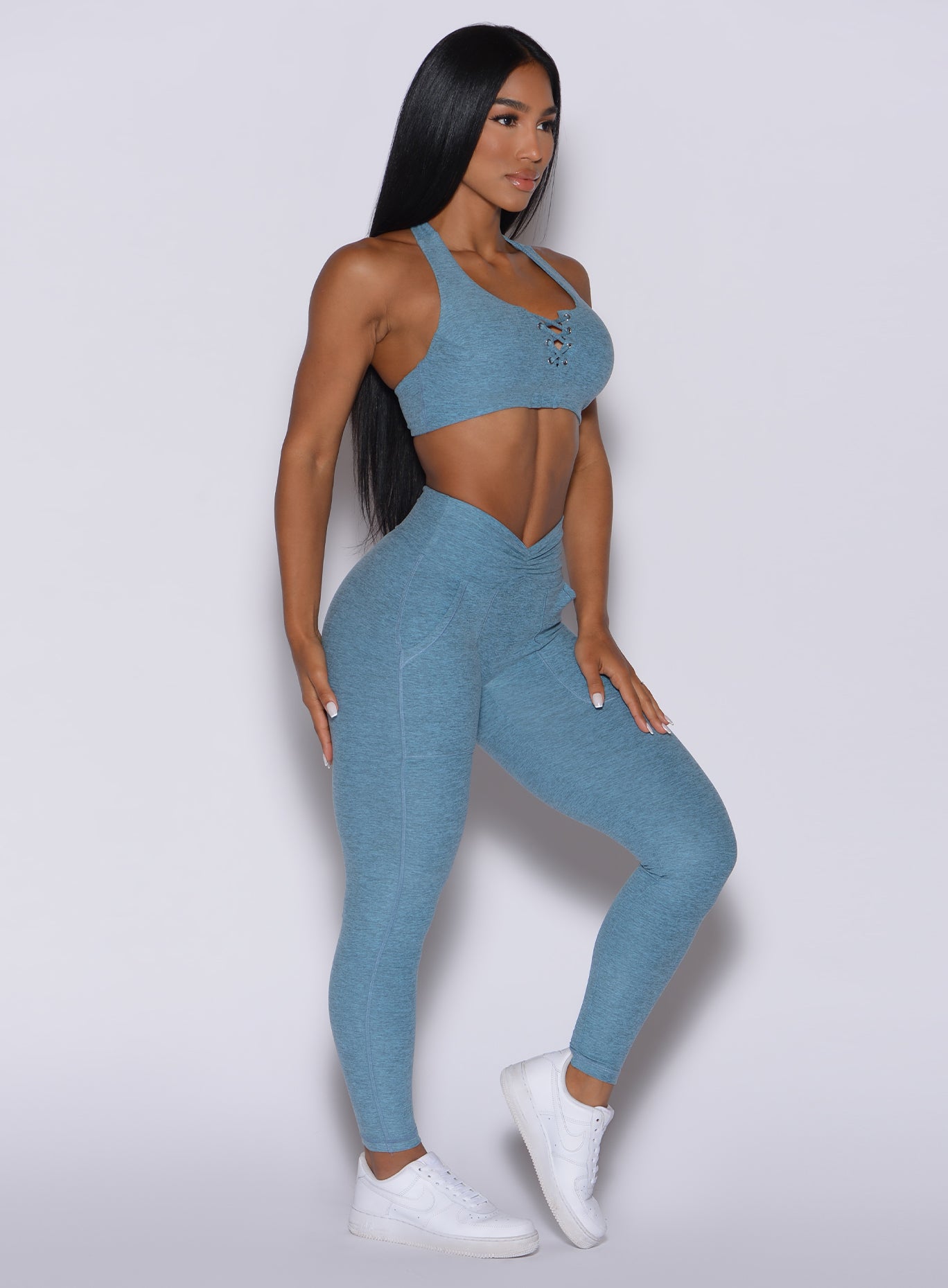 Right side profile view of a model angled to her right wearing our V scrunch leggings in baby blue color and a matching bra
