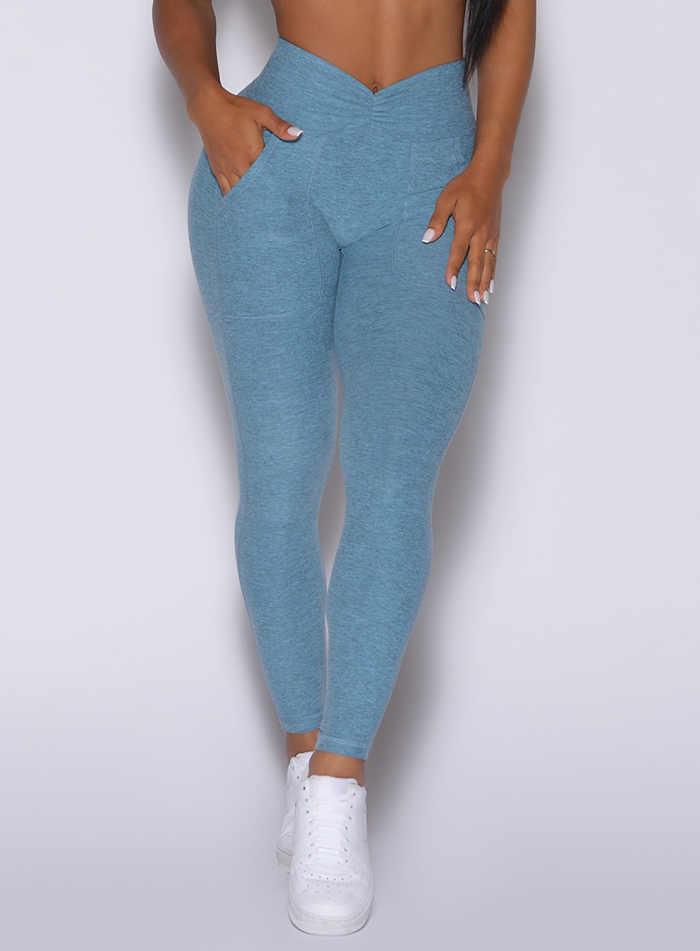 Zoomed in front profile view of a model wearing our V scrunch leggings in baby blue color