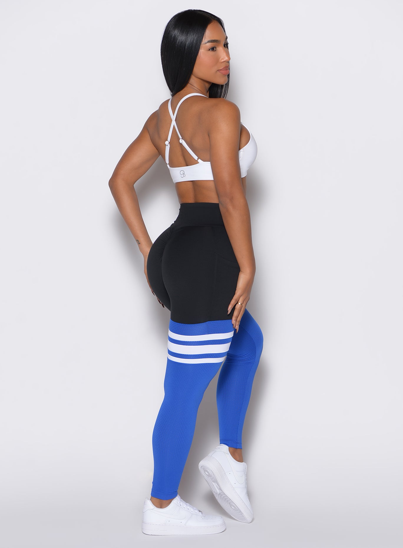 Right side profile view of a model facing to her right wearing our Scrunch Thigh Highs in Black and Sky color along with a white bra