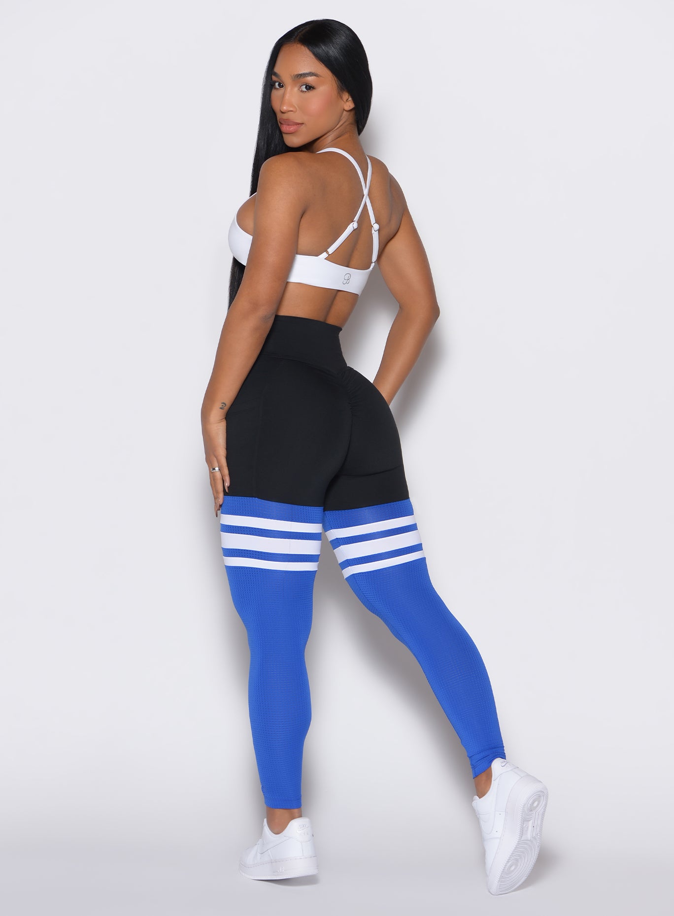 Left profile view of a model facing to her left wearing our Scrunch Thigh Highs in Black and Sky color along with a white bra 