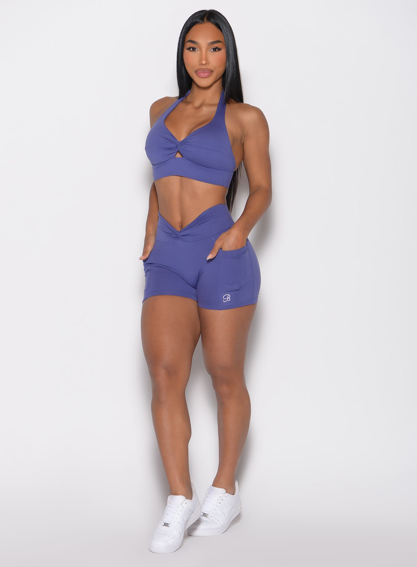 front profile view of a model with both hands inside the side pockets wearing the Sculpt Knot Shorts in future dusk color