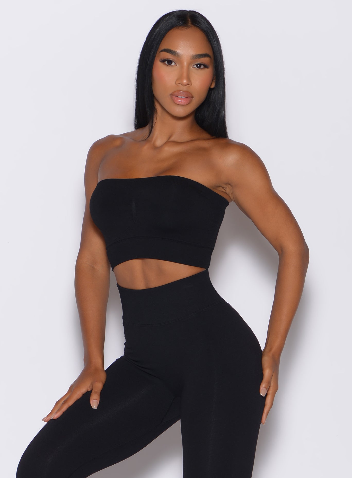 front side profile picture of a model facing forward, wearing our black seamless bandeau along with the matching leggings