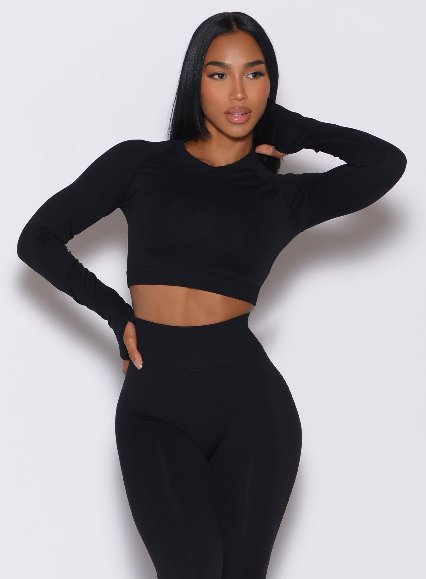 Front profile view of a model wearing our black seamless pullover along with a matching leggings