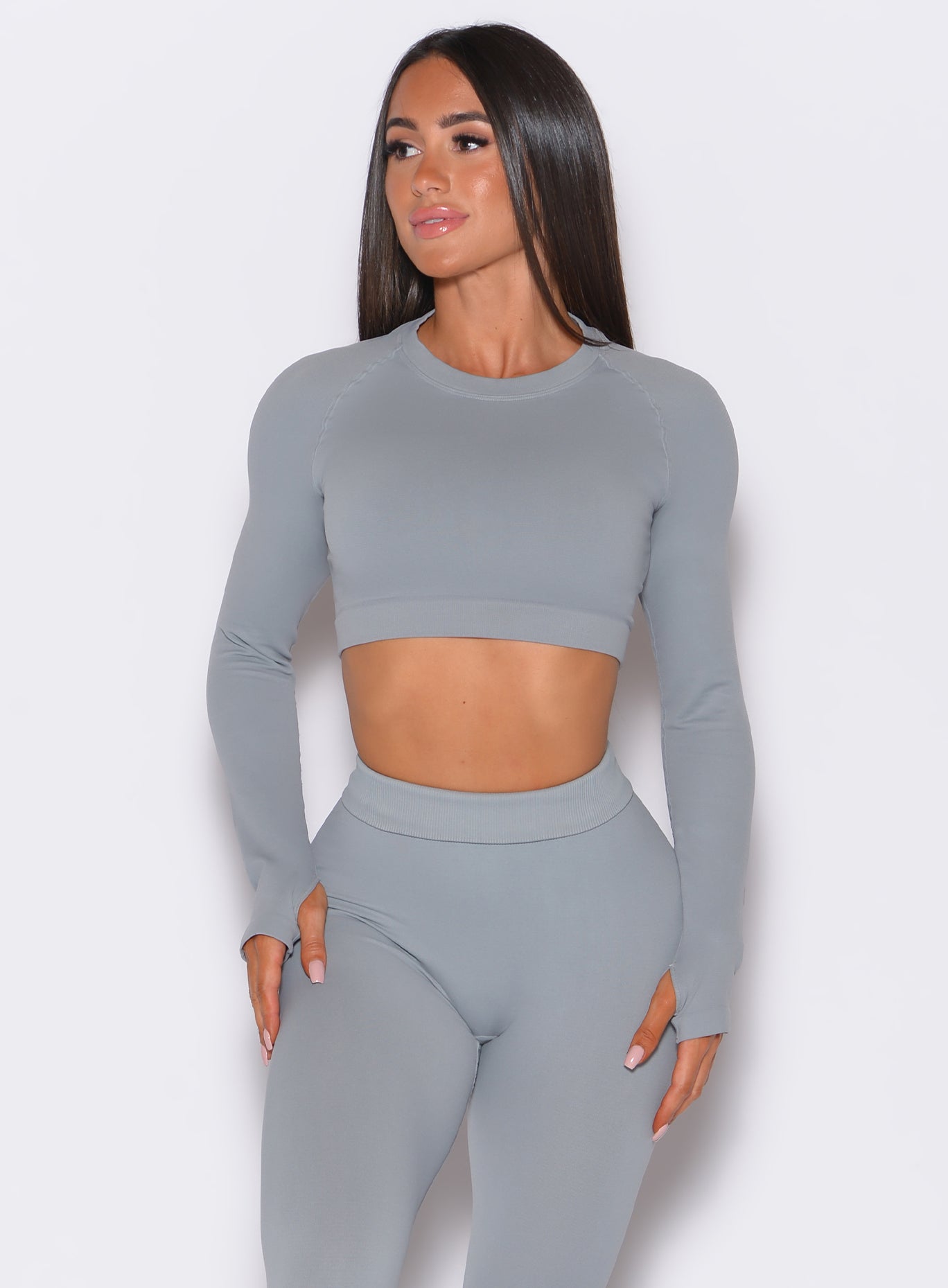 front side profile view of a model facing to her right wearing our seamless pullover in fog gray color along with a matching leggings