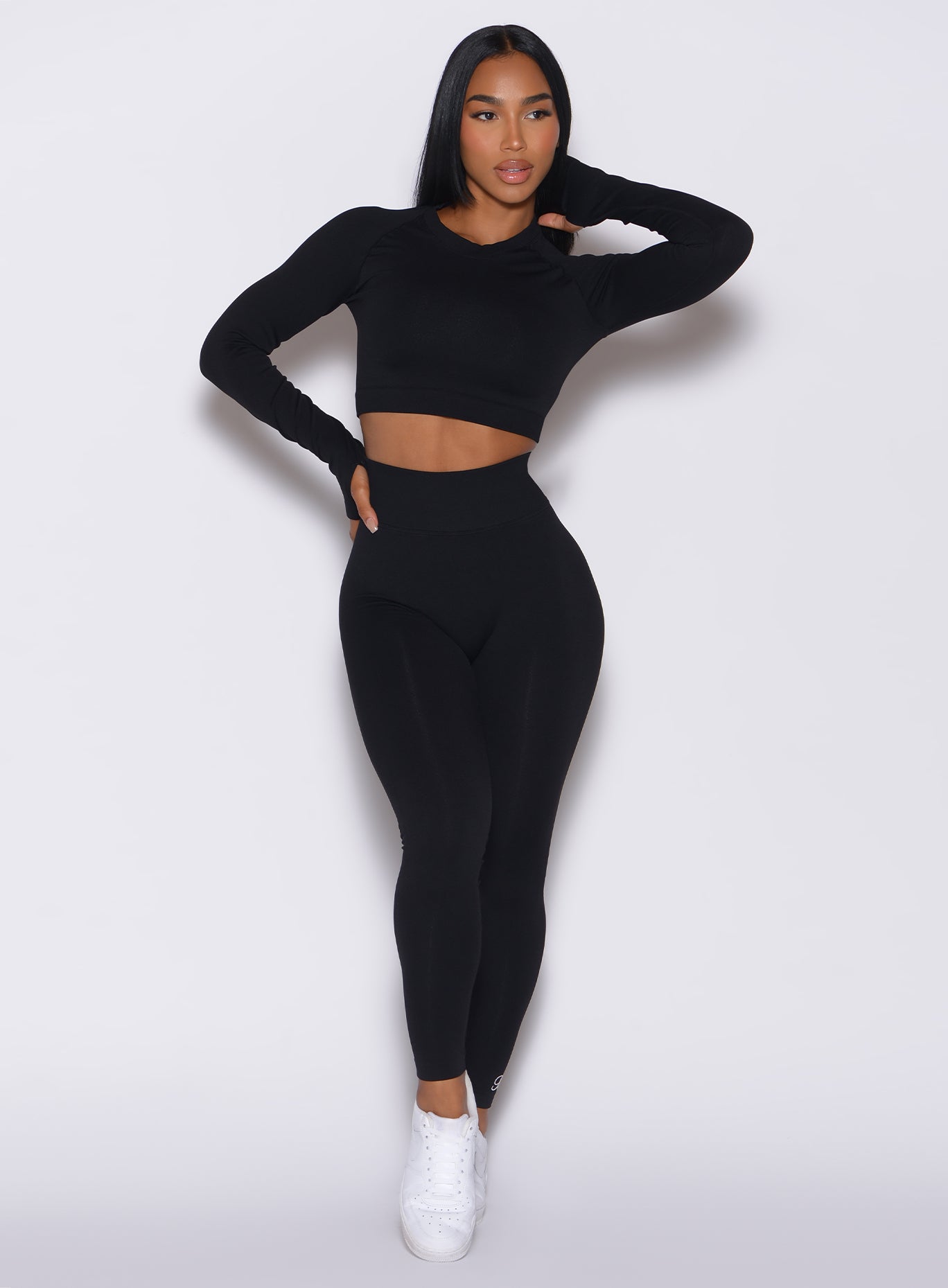 Front profile view of a model wearing our black Cheeky Seamless Leggings along with a matching bombshell pullover