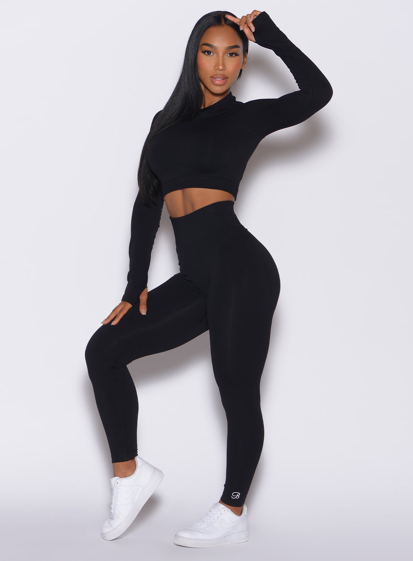 Front profile view of a model wearing our black Cheeky Seamless Leggings along with a matching pullover