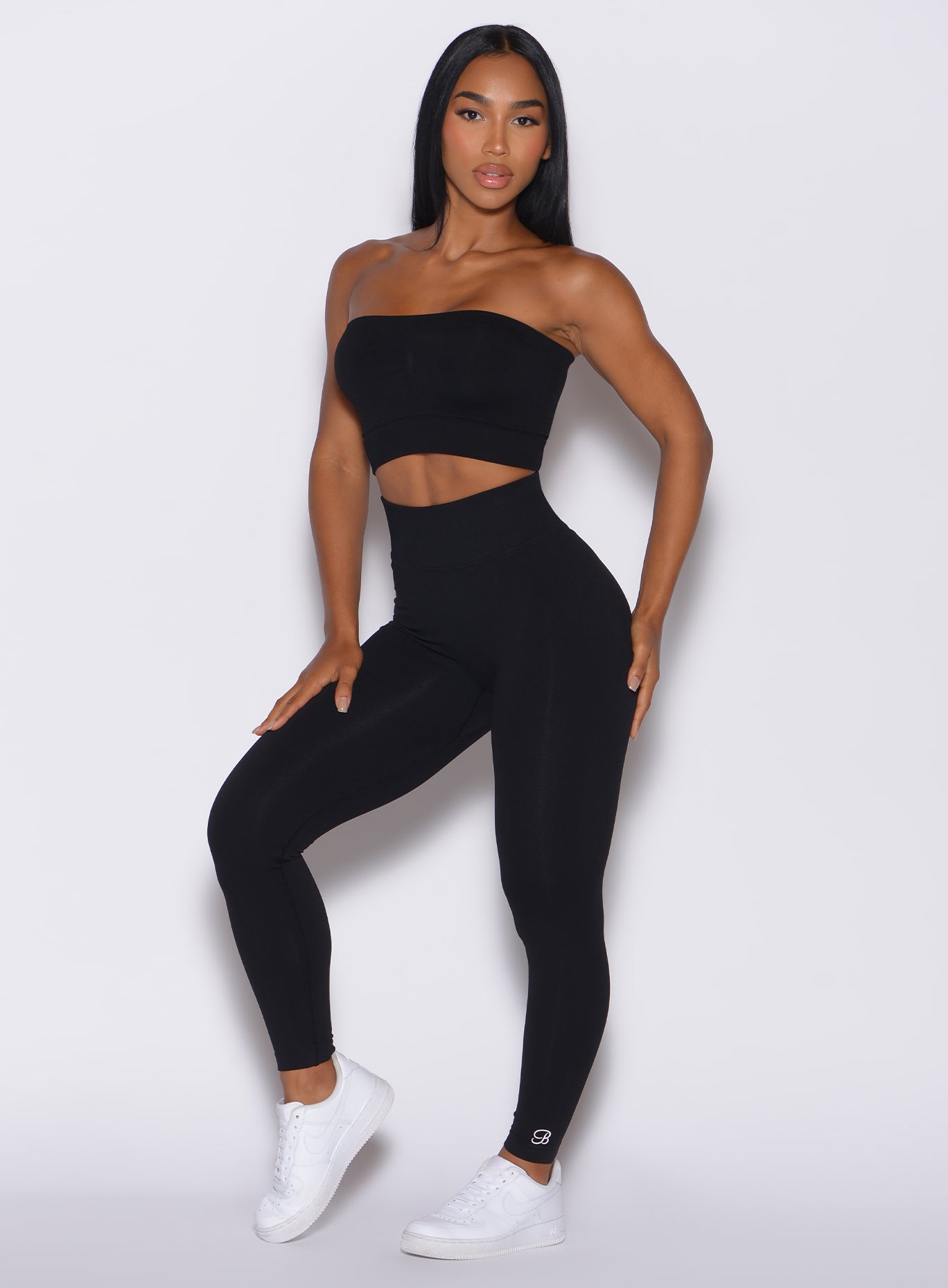 left side profile view of a model angled left wearing our black cheeky seamless leggings along with the matching bandeau