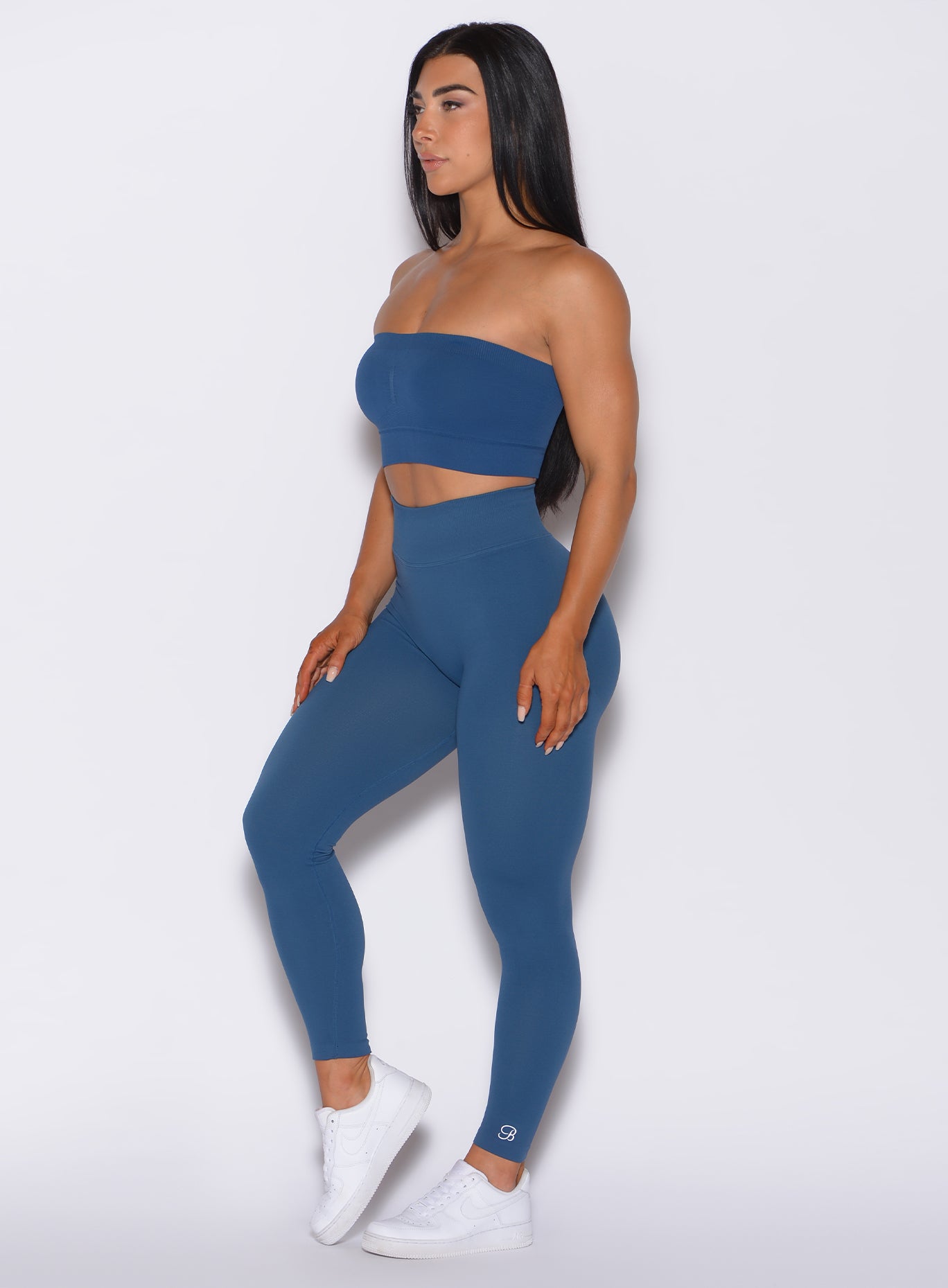 Left side profile view of a model facing forward wearing our cheeky seamless leggings in galaxy color along with the matching bandeau