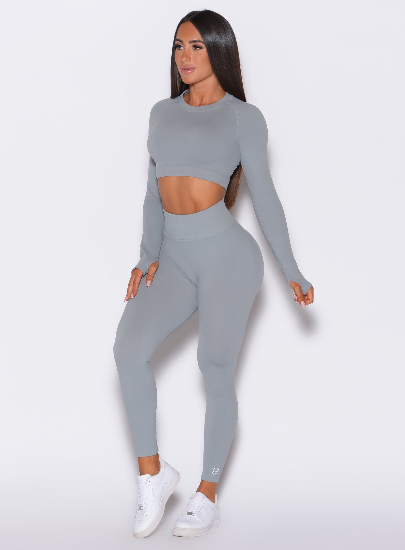 front profile view of a model wearing our cheeky seamless leggings in fog gray color along with a matching pullover