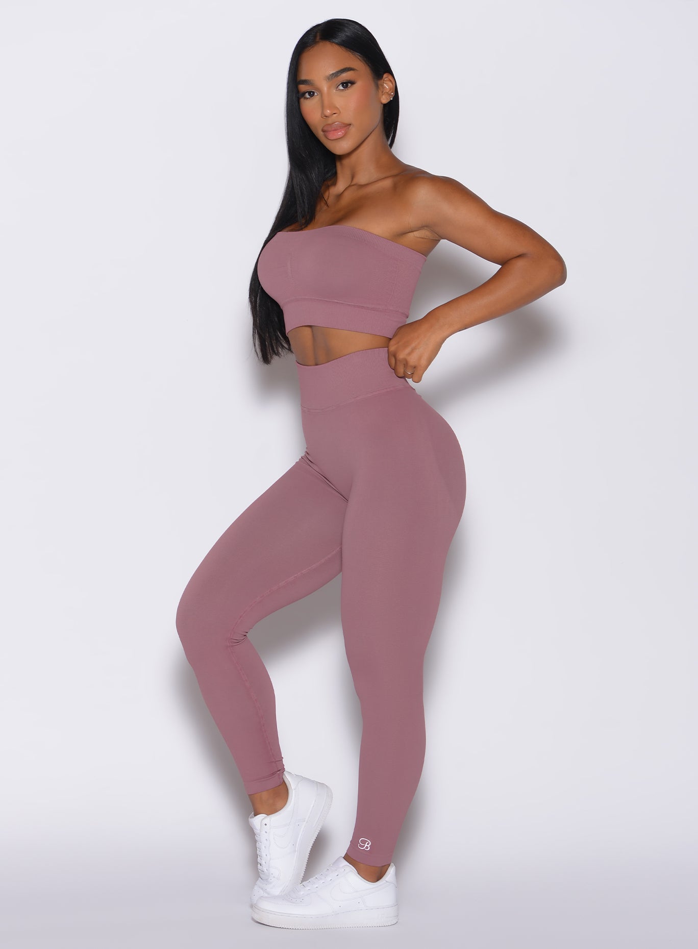 Left side profile view of a model angled left wearing our cheeky seamless leggings in satin color along with the matching bandeau