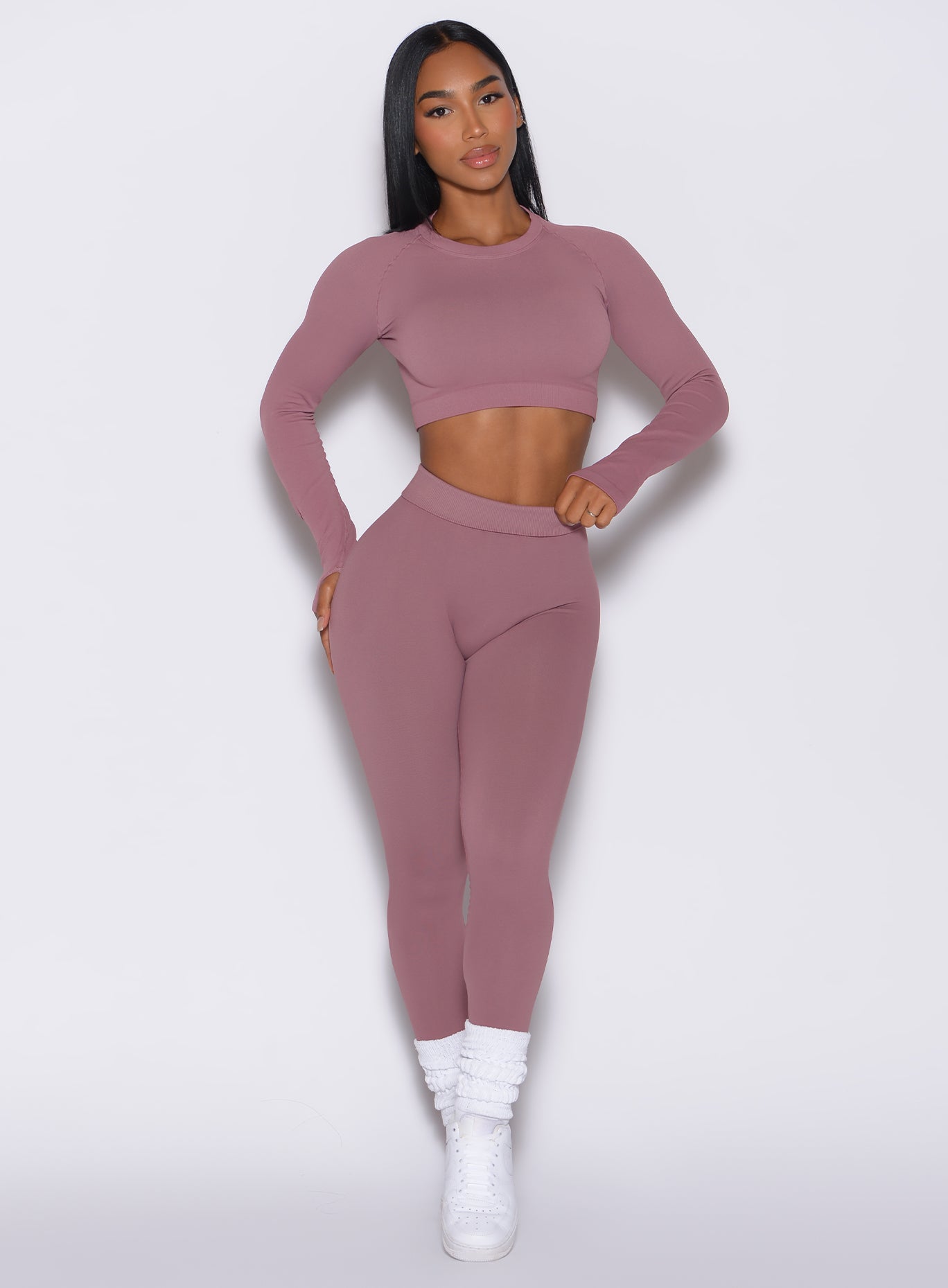 front profile view of a model facing forward wearing our cheeky seamless leggings in satin color along with the matching pullover