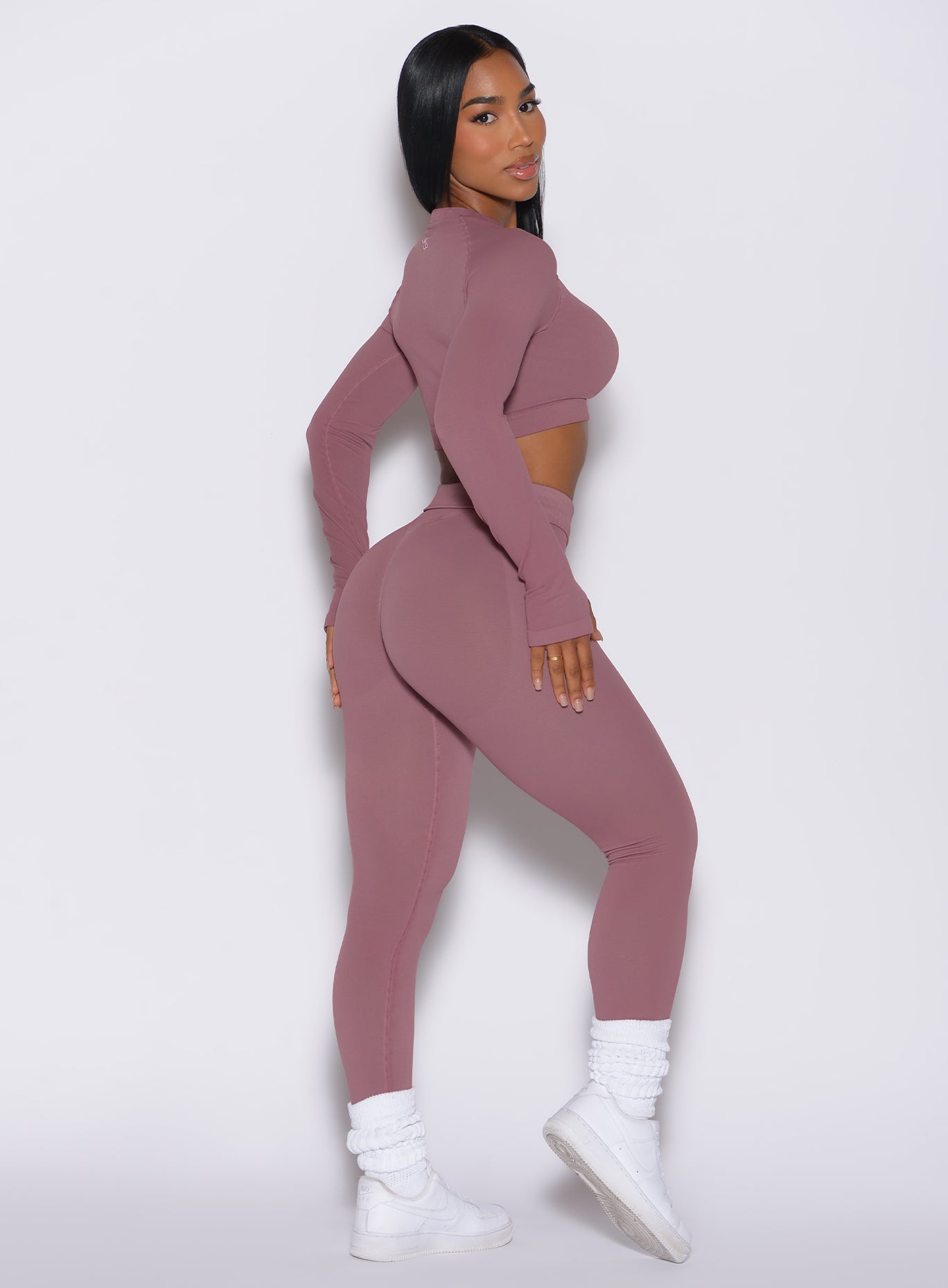 right side profile view of a model facing to her right wearing our cheeky seamless leggings in satin color along with the matching pullover