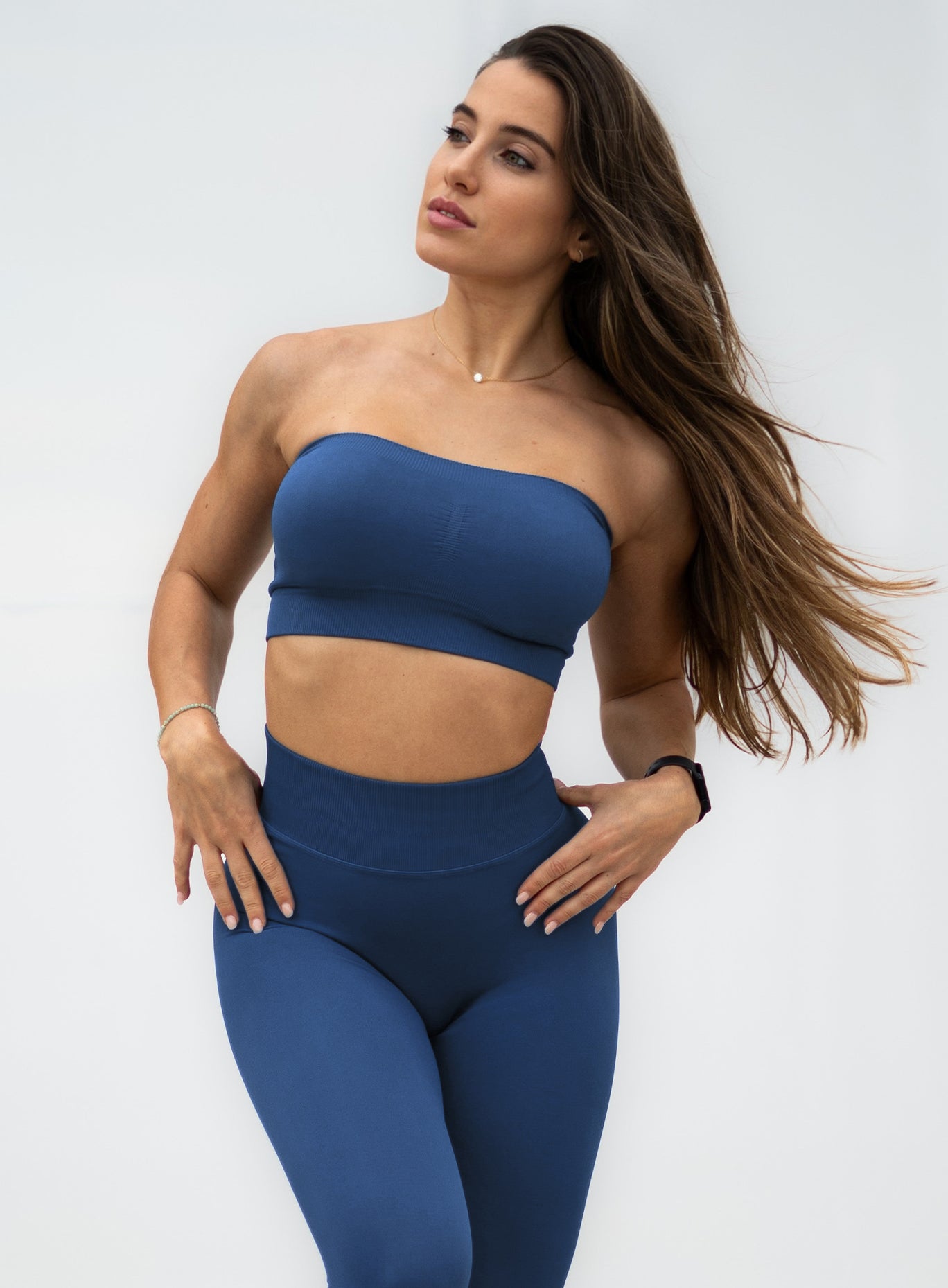 front profile view of a model with her hands on waist wearing our seamless bandeau in galaxy color along with the matching leggings